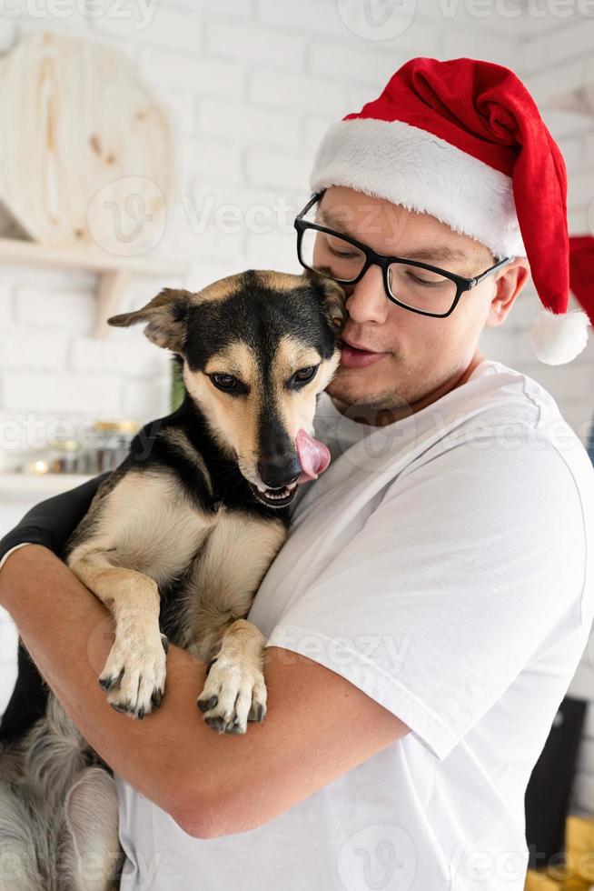 knappe hipster met zijn hond die kerstcake kookt in een keuken. foto