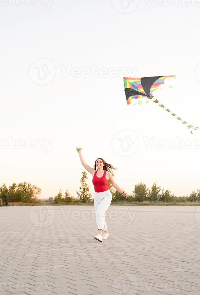 jonge vrouw die een vlieger vliegt in een openbaar park bij zonsondergang foto