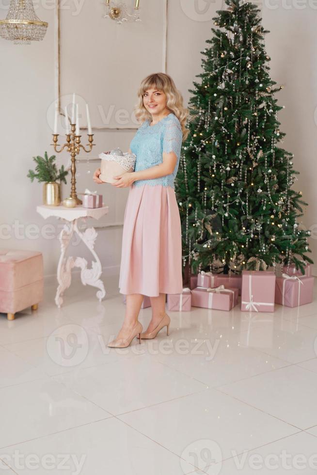 jonge vrouw versiert kerstboom met kerstspeelgoed foto
