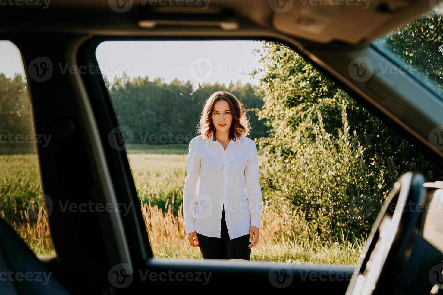 een mooie jonge vrouw in een wit overhemd rust buiten de stad foto