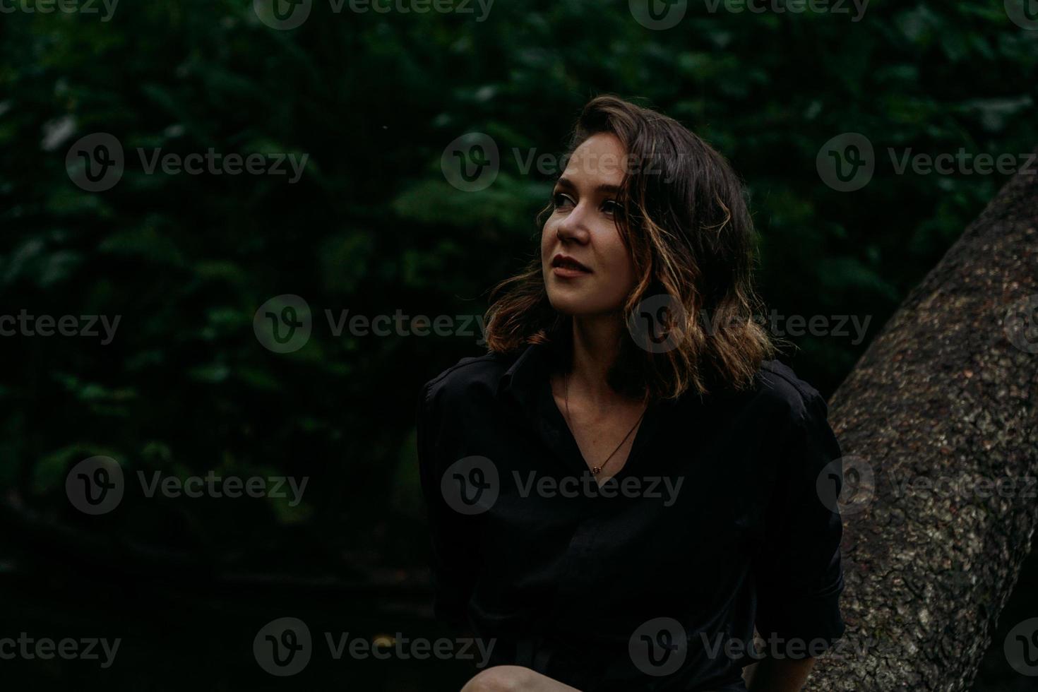 jonge vrouw - close portret in een donker bos. vrouw in zwart shirt foto