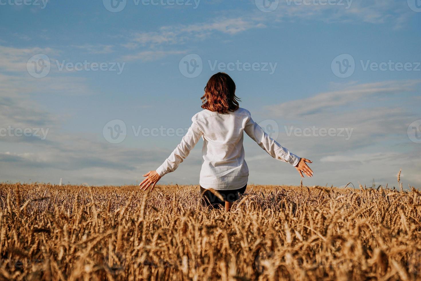 een vrouw in roggeveld. uitzicht vanaf de achterkant. het concept van harmonie foto