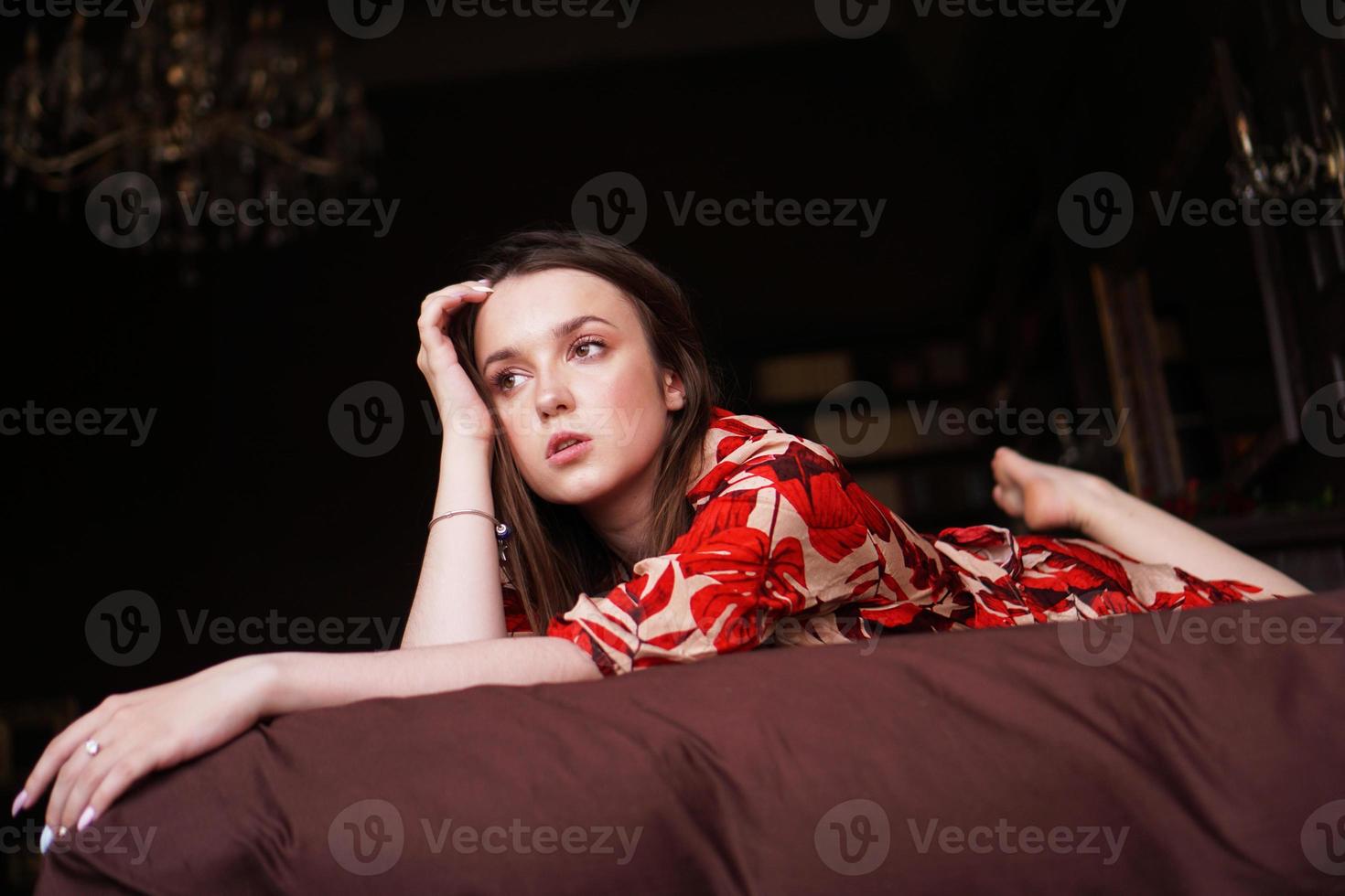 ontspannen vrouw liggend op een bruin bed diep nadenkend foto