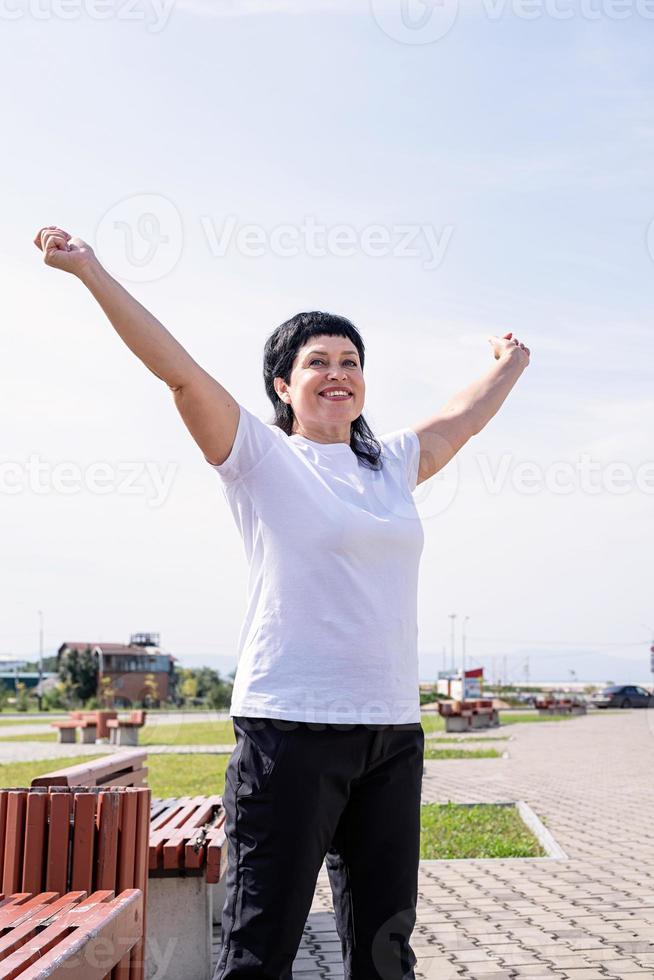 Senior vrouw doet warming-up voordat ze buiten in het park gaat trainen foto