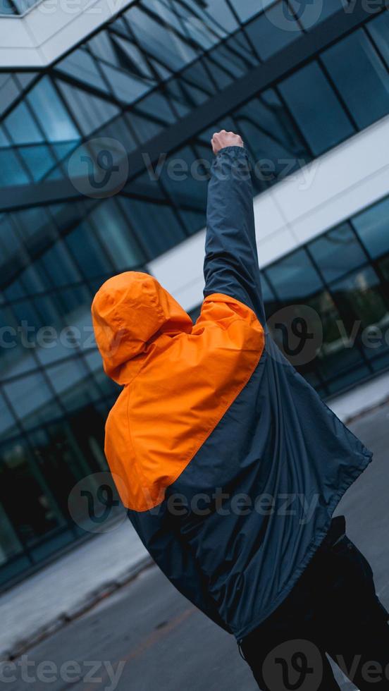 jonge man in oranje werkuniform - glazen gebouw op achtergrond foto