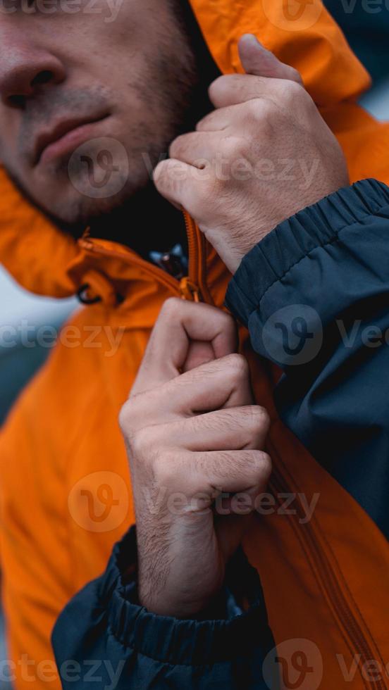 een man maakt zijn werkuniform vast. oranje arbeidersuniform - close-up foto