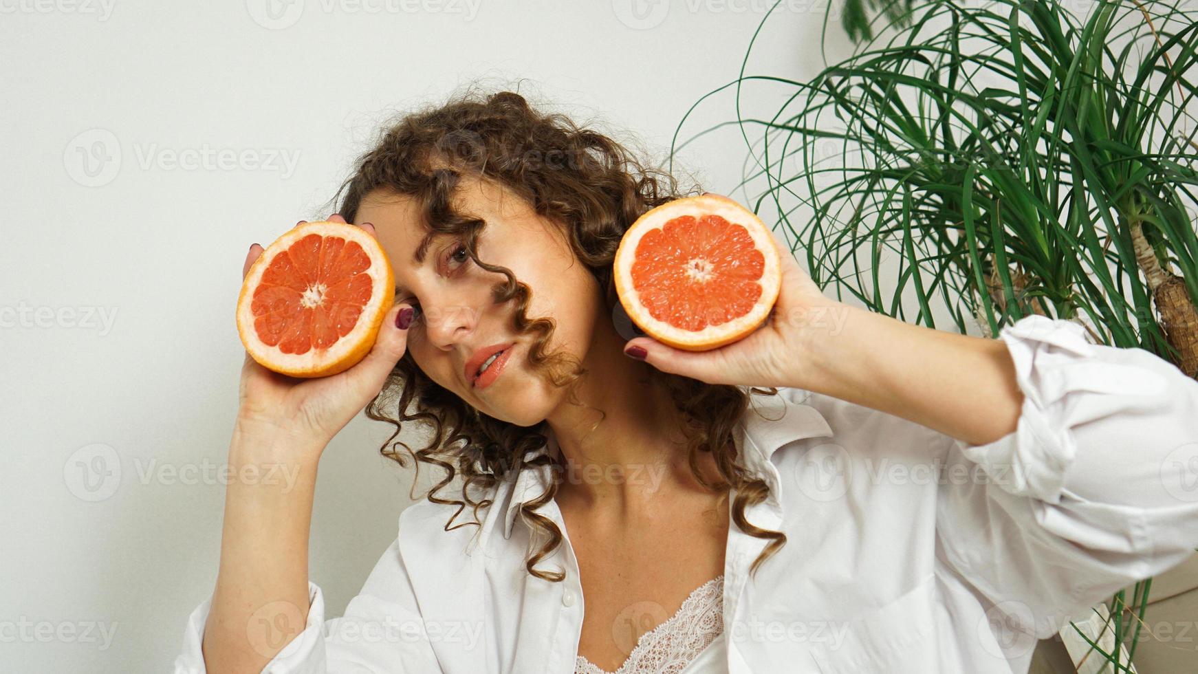 portret van mooie vrouw van middelbare leeftijd met krullend haar met grapefruit foto