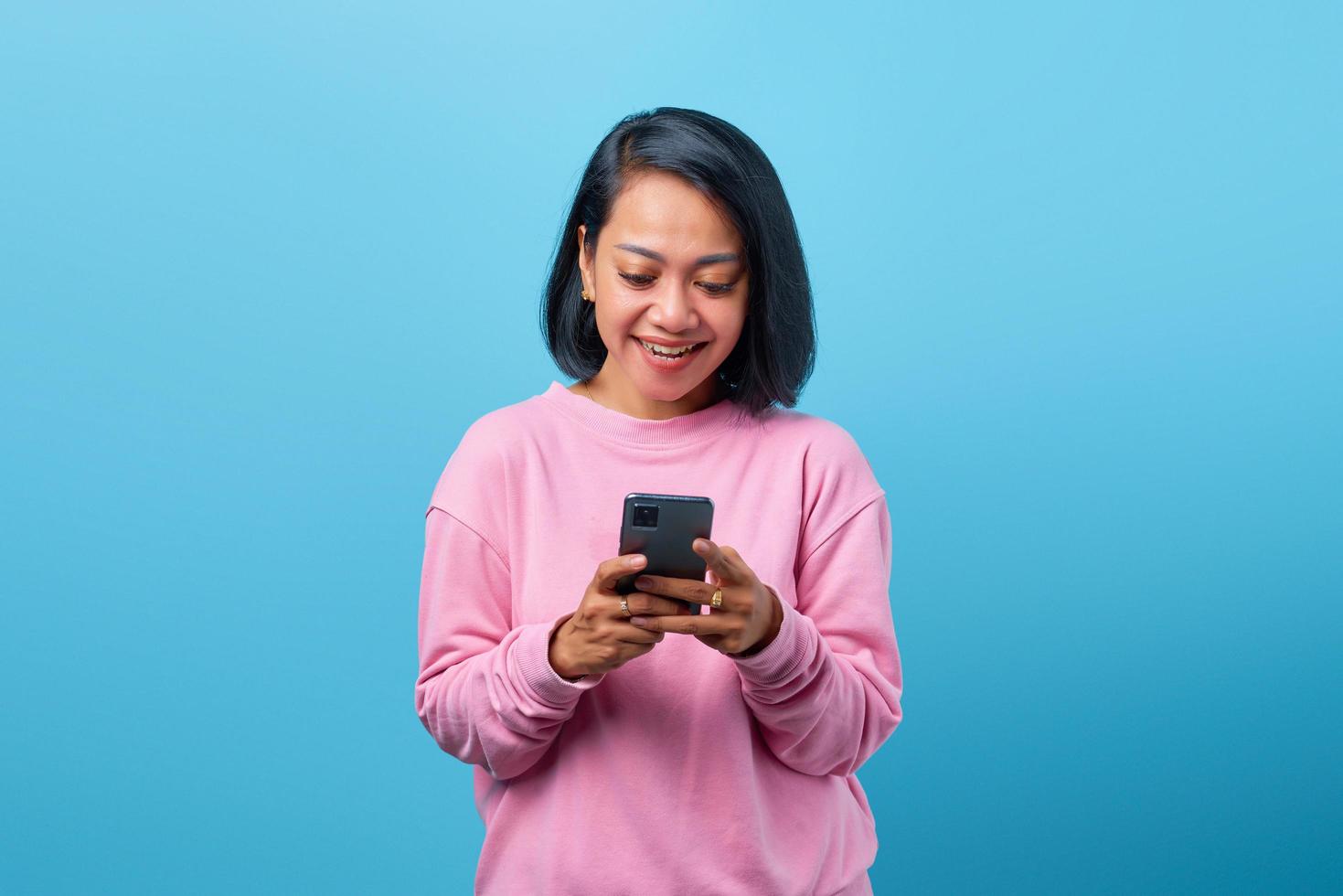 mooie aziatische vrouw die lacht op zoek naar smartphone foto