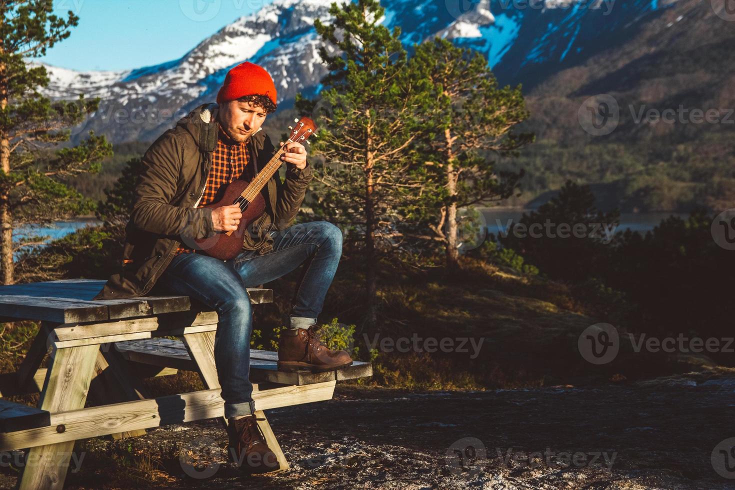 man die gitaar speelt tegen de achtergrond van bergen, bossen foto
