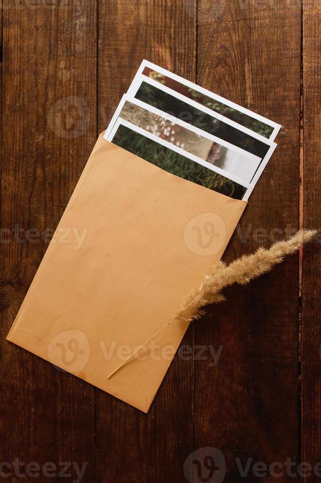foto's zijn ingesloten in een beige envelop, gelegen op een bruine houten tafel foto
