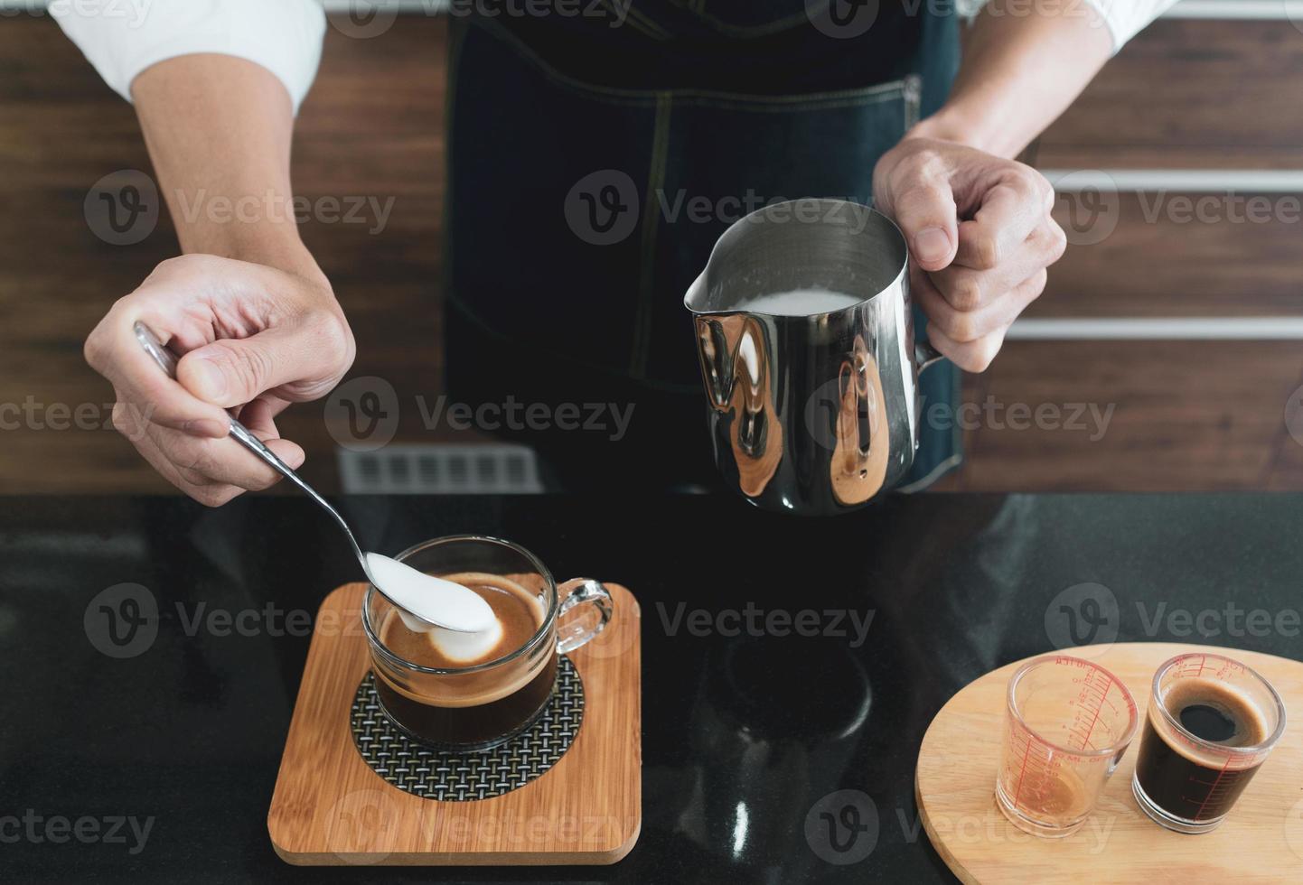 bariata die melkschuim in cappuccinokopje scheppen foto