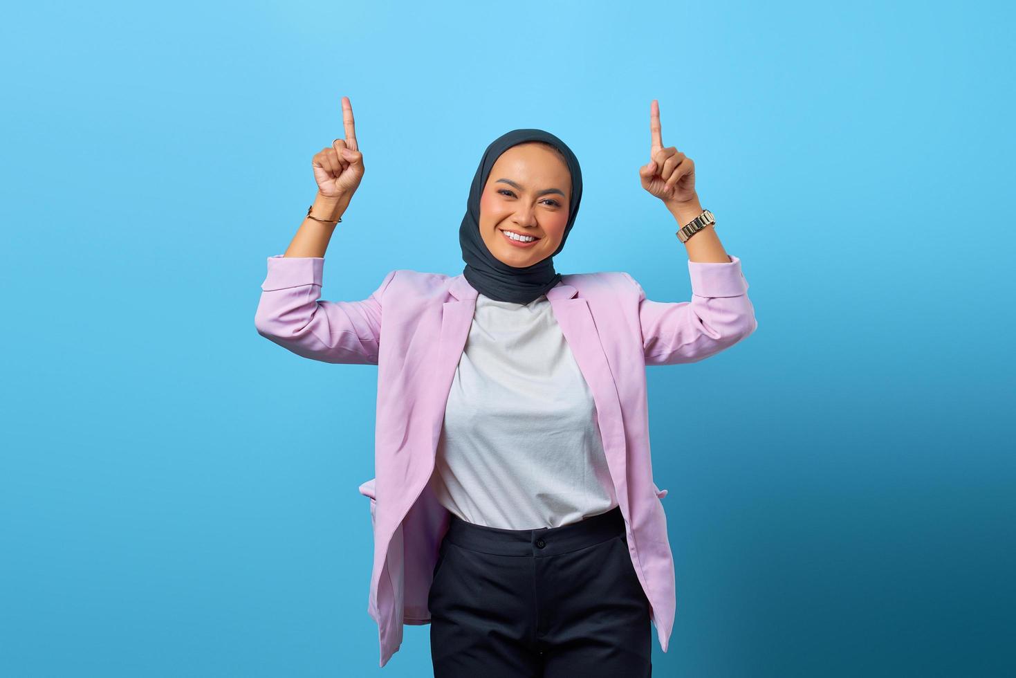 portret van vrolijke aziatische vrouw die omhoog wijst over blauwe achtergrond foto