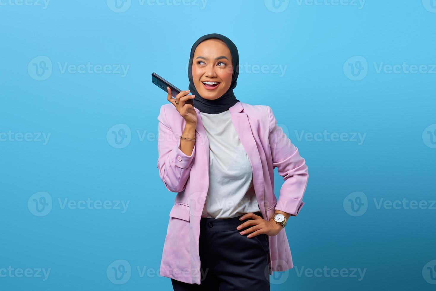 vrolijke aziatische vrouw die mobiele telefoon over blauwe achtergrond gebruikt foto