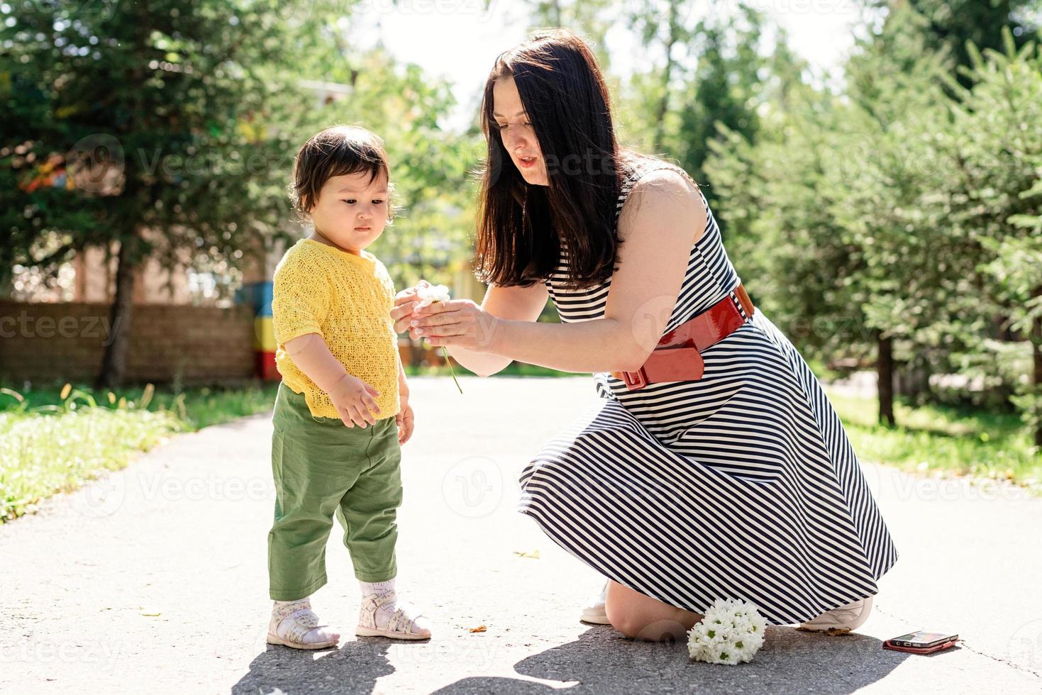 moeder loopt met haar dochter in het park en geeft haar bloemen foto