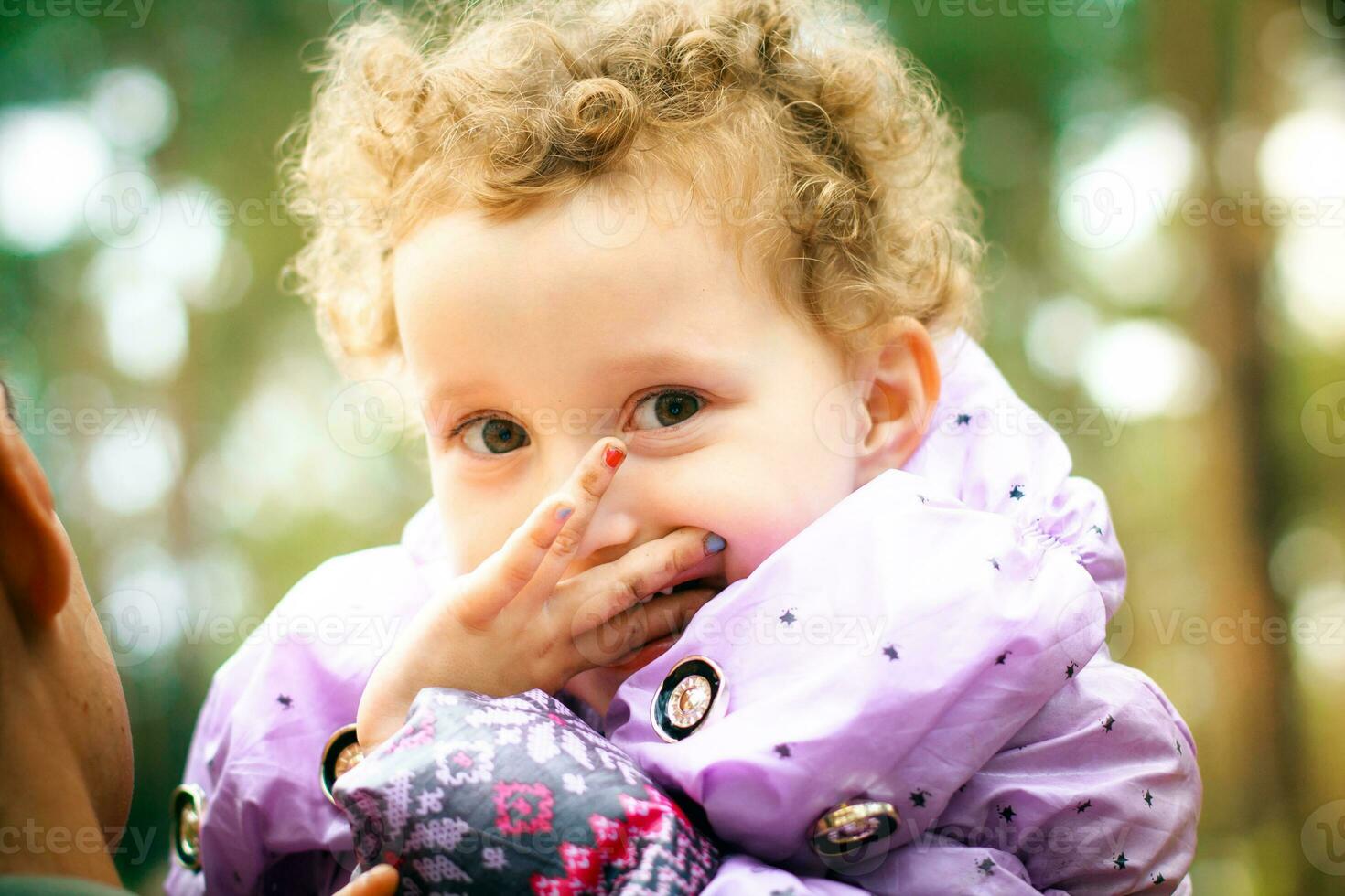 de weinig meisje houdt een hand- in de buurt de gezicht. vingers kind met geschilderd nagels. gelukkig baby in de armen van zijn vader foto