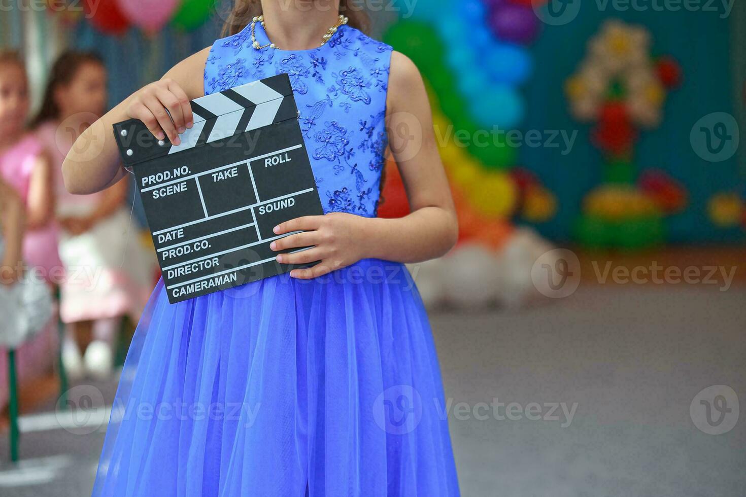 Filmklapper in de handen van een meisje in een blauw avond jurk. foto