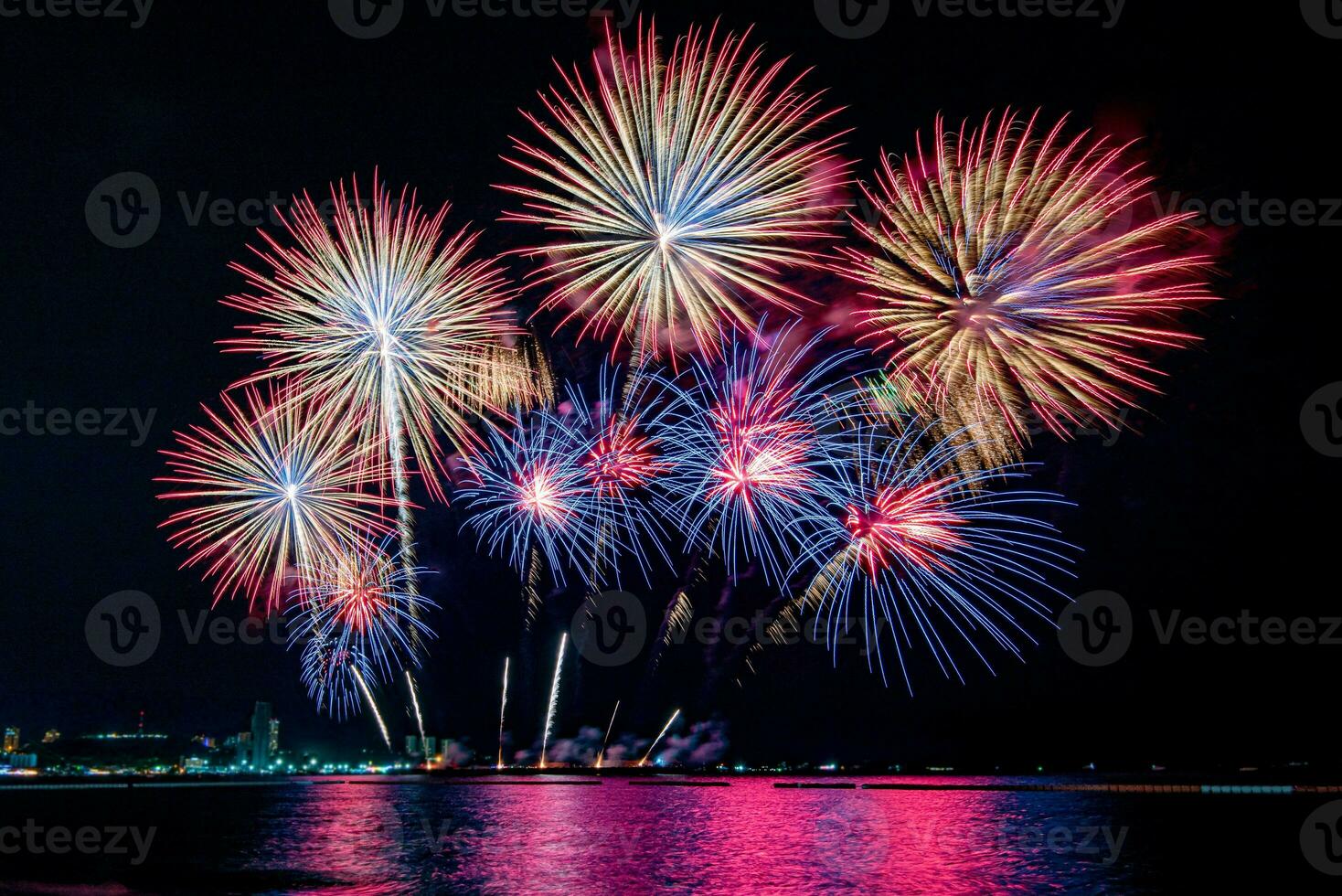 geweldig mooi kleurrijk vuurwerk op de feestavond, te zien op het zeestrand met veelkleurige reflectie op water foto