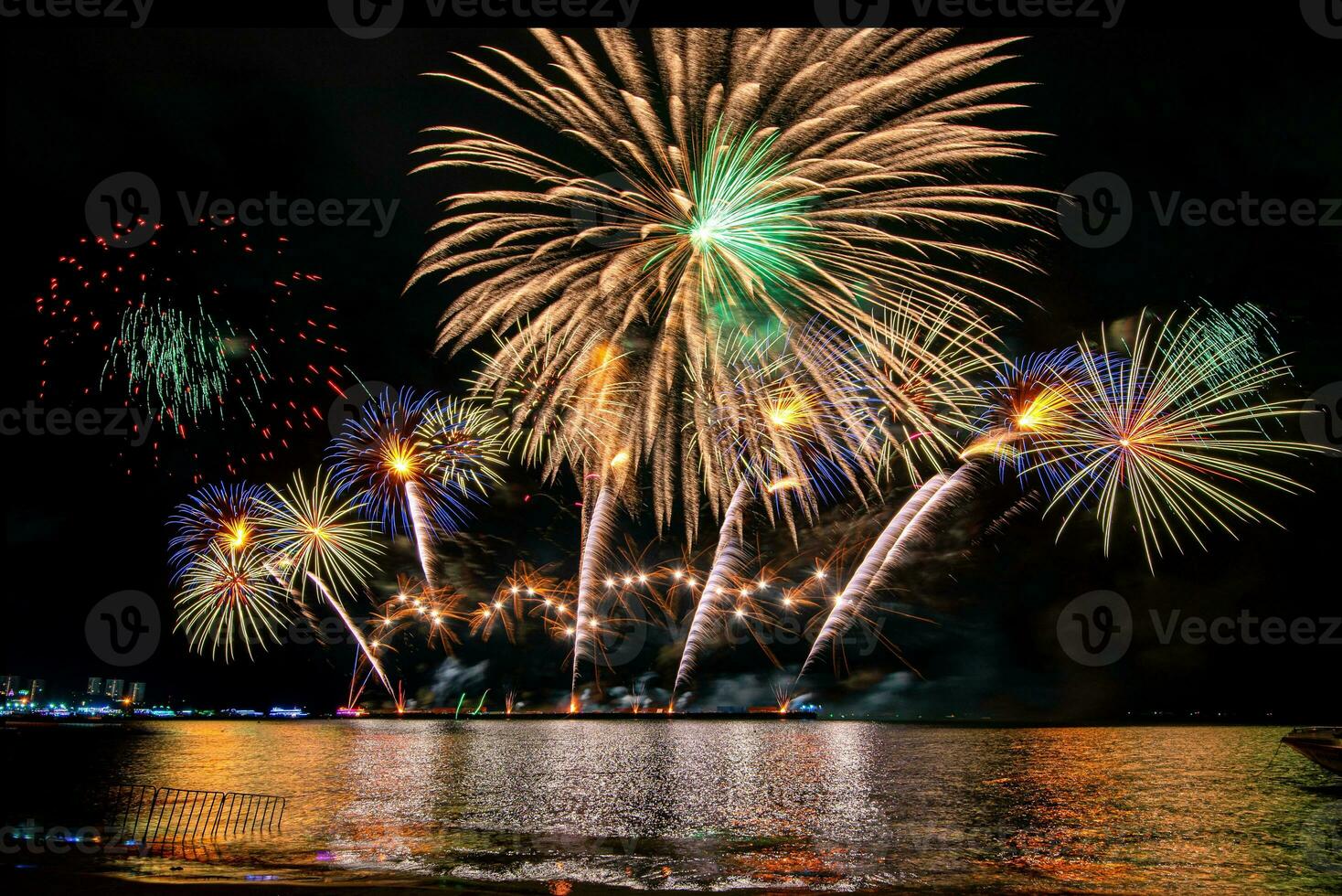 geweldig mooi kleurrijk vuurwerk op de feestavond, te zien op het zeestrand met veelkleurige reflectie op water foto