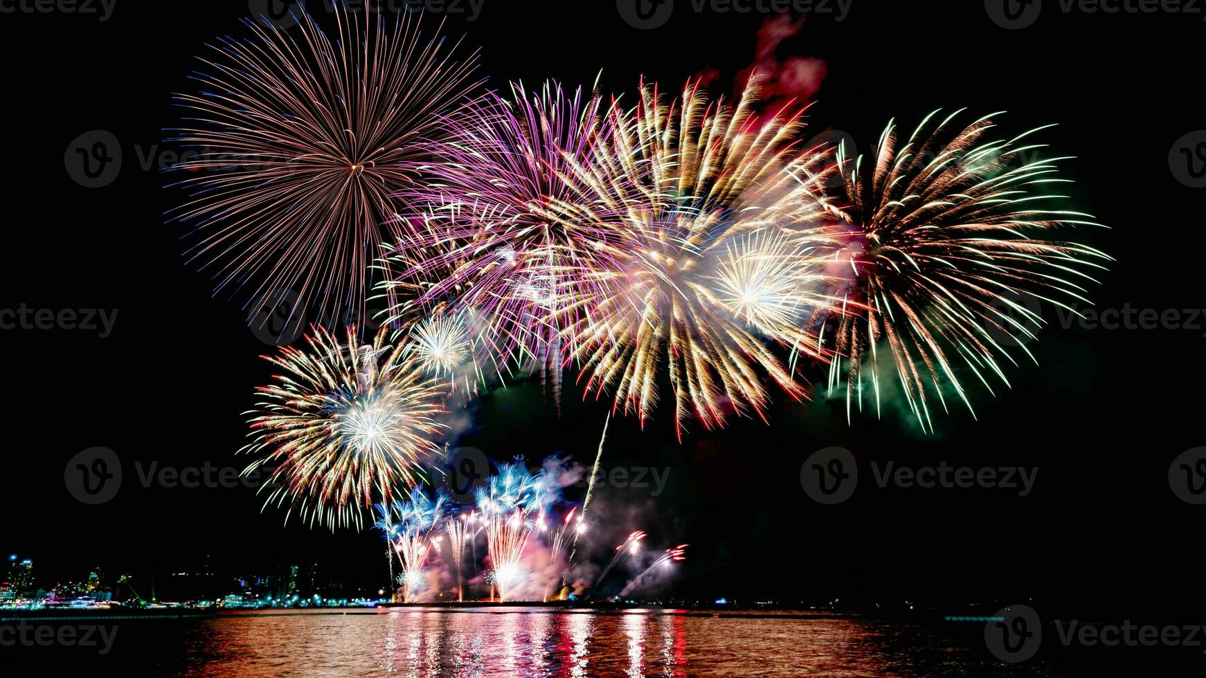 geweldig mooi kleurrijk vuurwerk op de feestavond, te zien op het zeestrand met veelkleurige reflectie op water foto