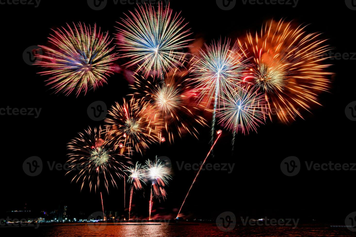 geweldig mooi kleurrijk vuurwerk op de feestavond, te zien op het zeestrand met veelkleurige reflectie op water foto