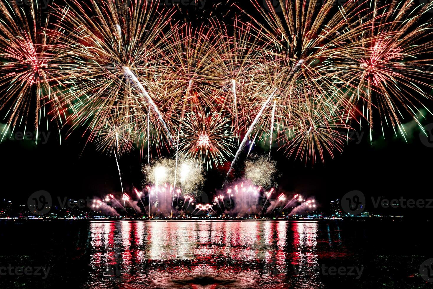 geweldig mooi kleurrijk vuurwerk op de feestavond, te zien op het zeestrand met veelkleurige reflectie op water foto