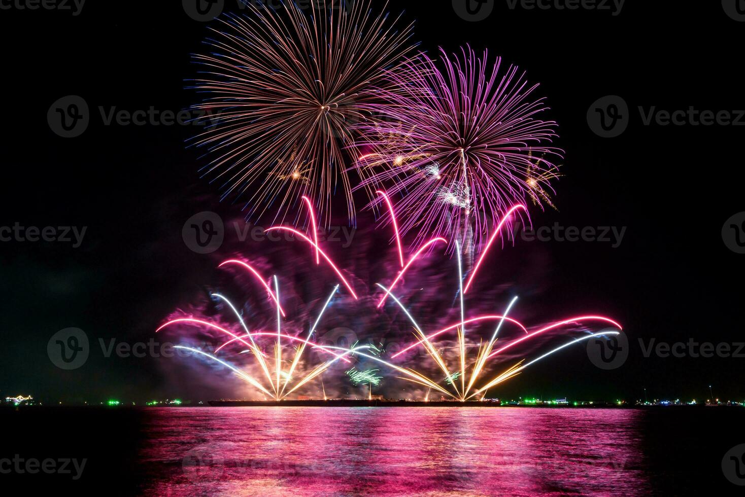 geweldig mooi kleurrijk vuurwerk op de feestavond, te zien op het zeestrand met veelkleurige reflectie op water foto