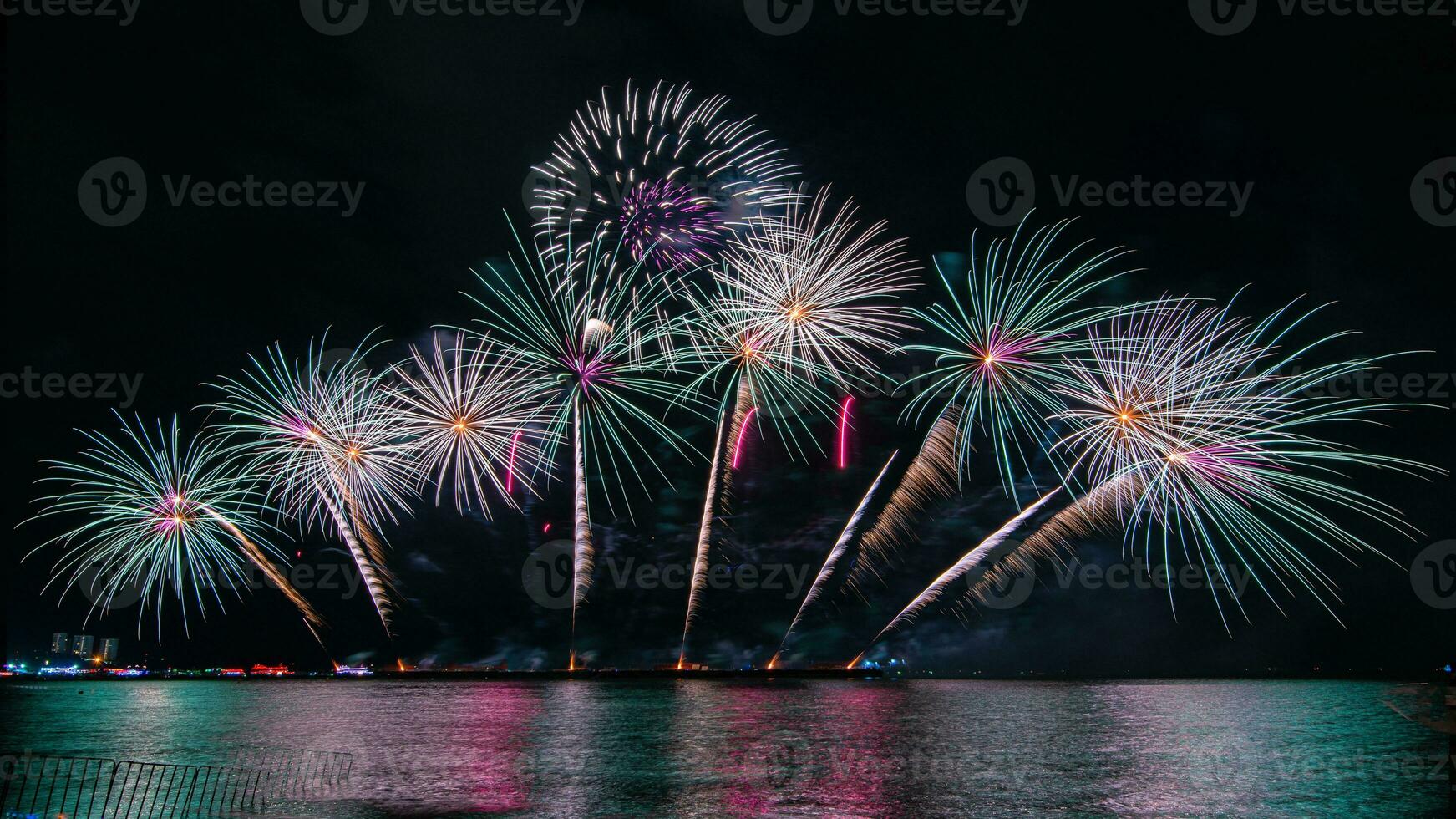 geweldig mooi kleurrijk vuurwerk op de feestavond, te zien op het zeestrand met veelkleurige reflectie op water foto