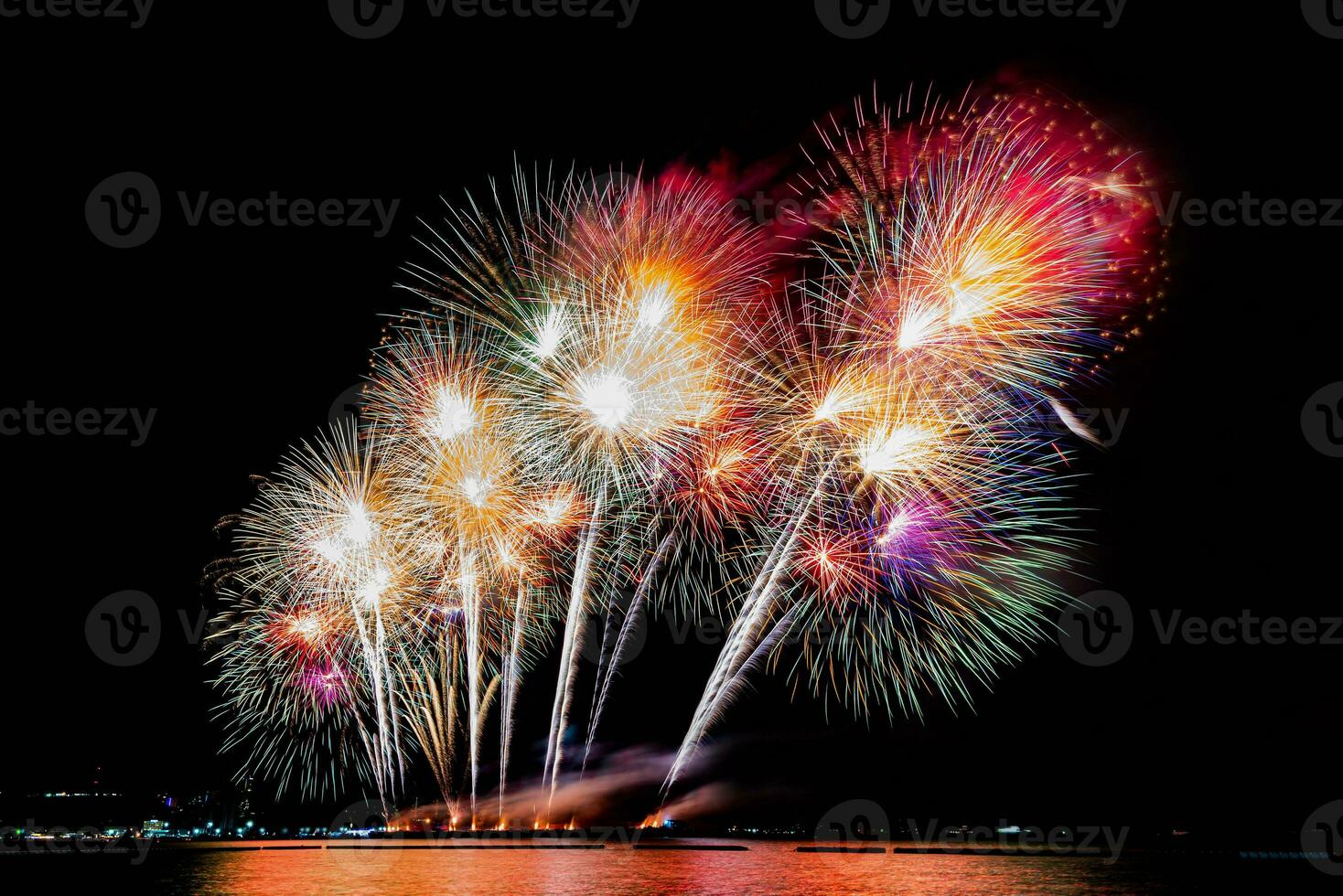 geweldig mooi kleurrijk vuurwerk op de feestavond, te zien op het zeestrand met veelkleurige reflectie op water foto