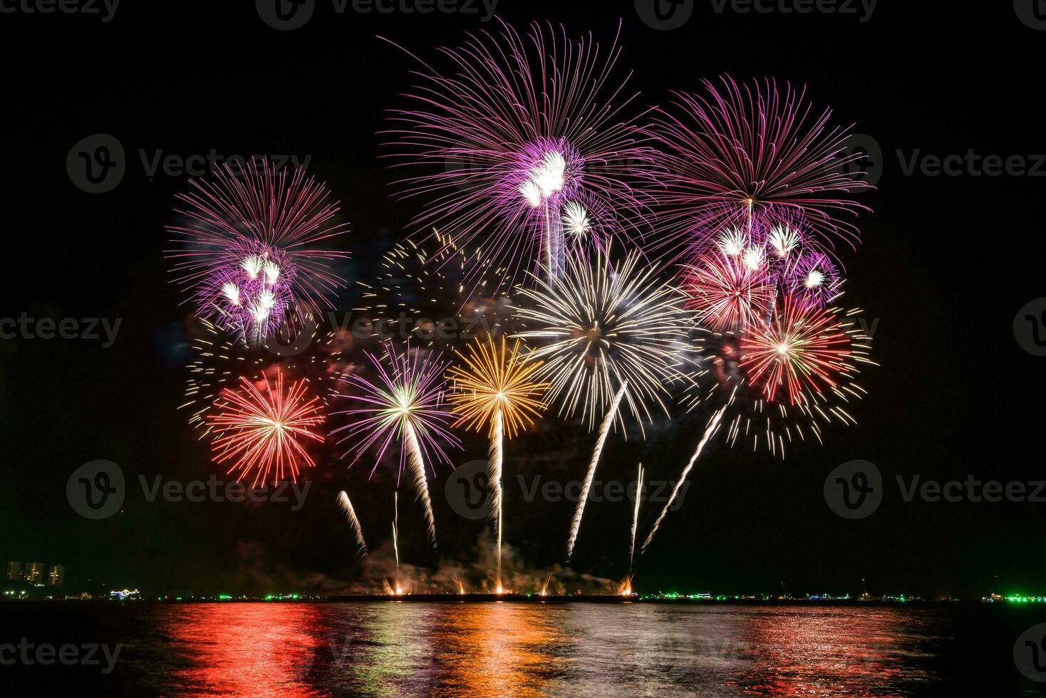 geweldig mooi kleurrijk vuurwerk op de feestavond, te zien op het zeestrand met veelkleurige reflectie op water foto