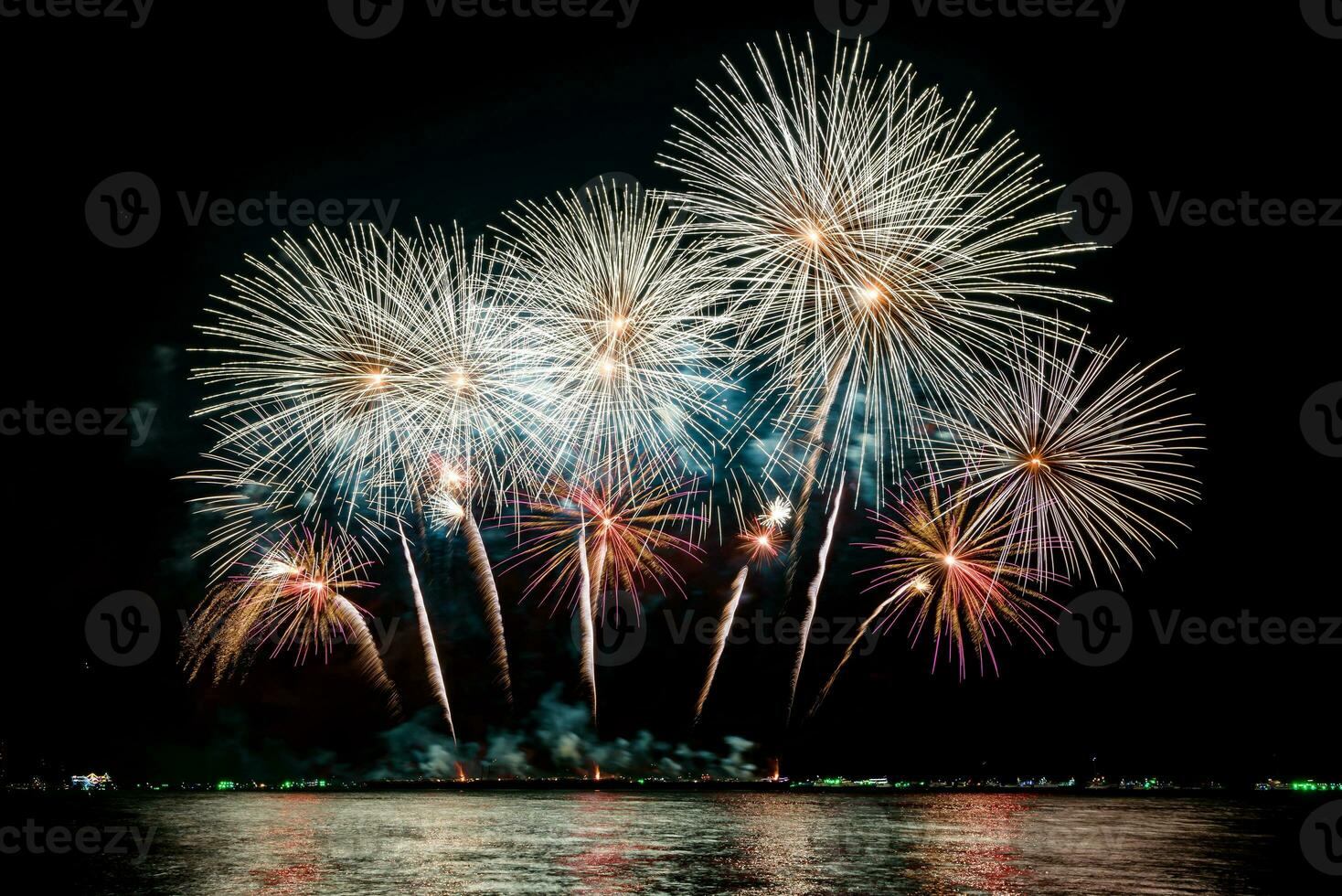 geweldig mooi kleurrijk vuurwerk op de feestavond, te zien op het zeestrand met veelkleurige reflectie op water foto