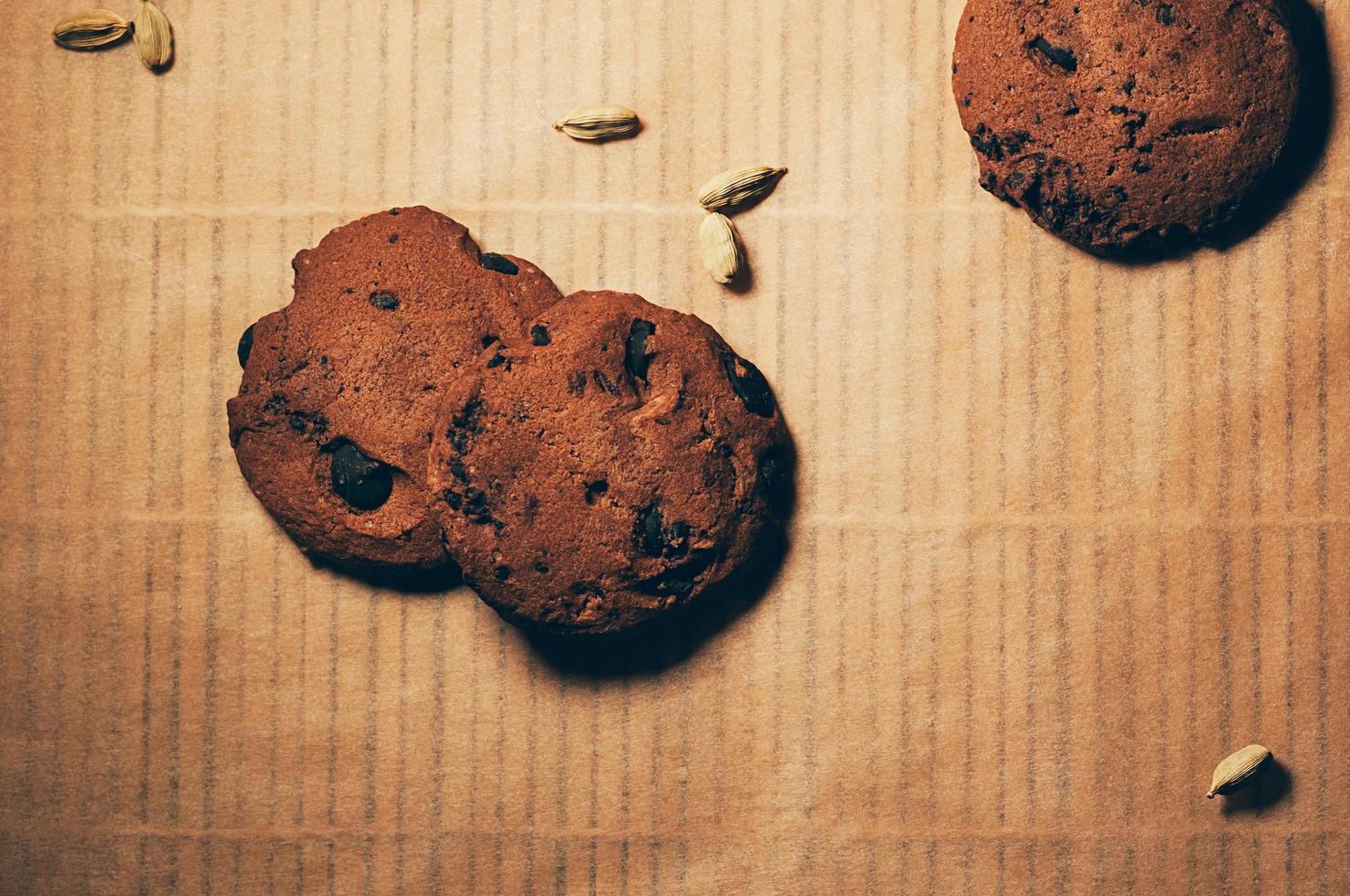 bovenaanzicht van knapperige chocoladekoekjes met kardemom op getextureerde perkamentachtergrond. ruimte voor uw tekst en ontwerp foto