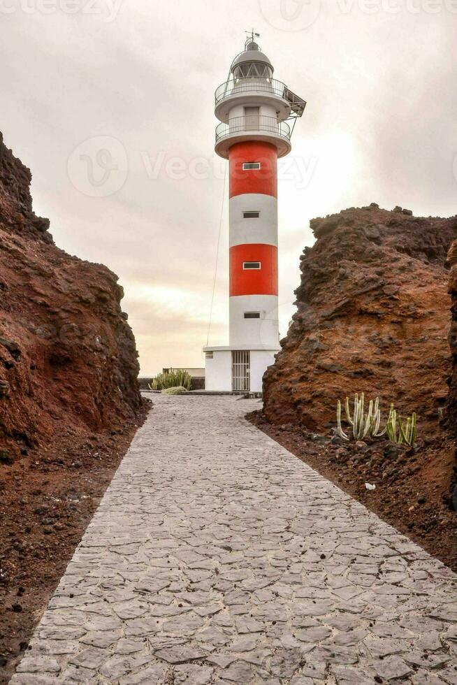 een rood en wit vuurtoren staat in de midden- van een rotsachtig Oppervlakte foto