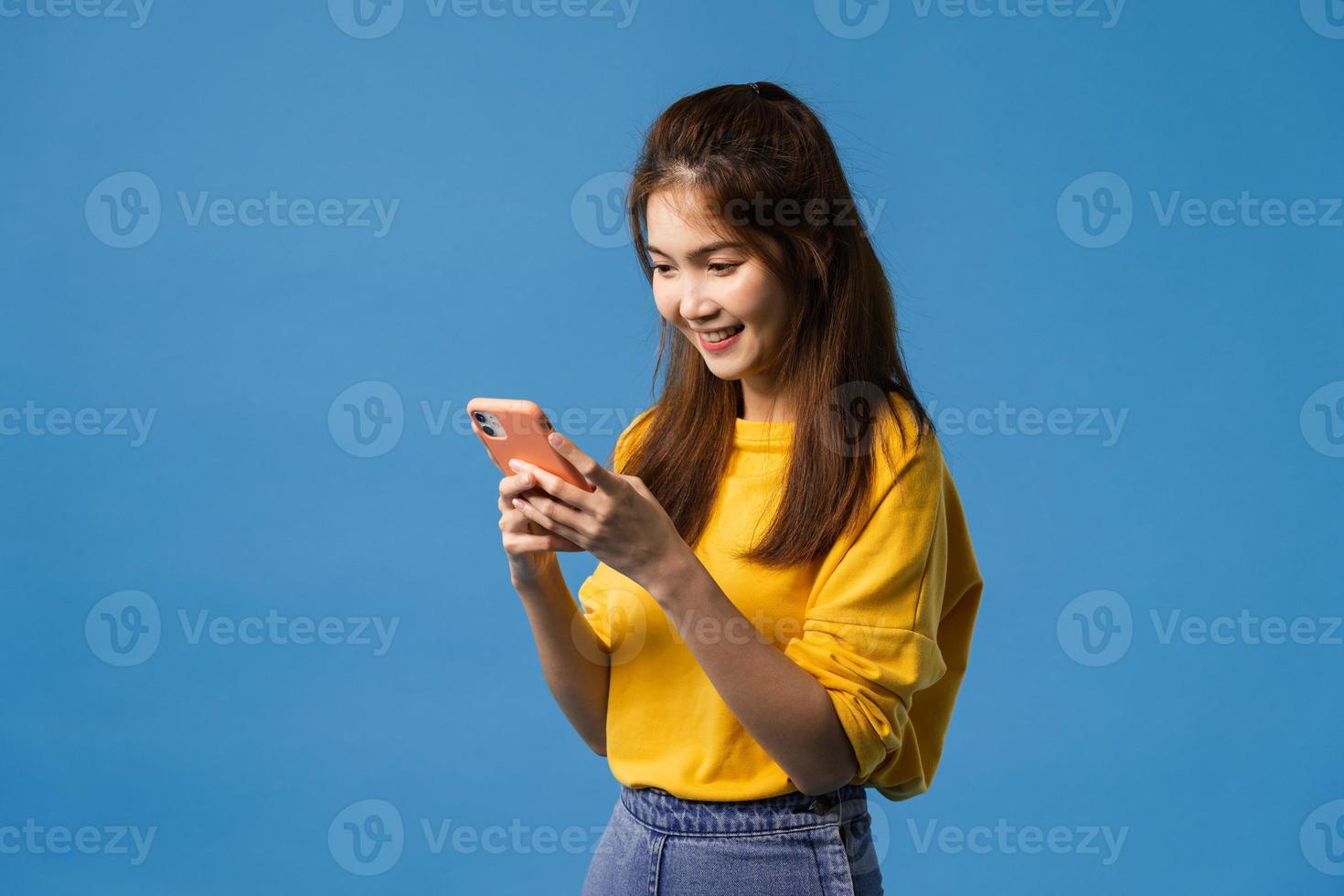 jonge dame met behulp van telefoon met positieve uitdrukking op blauwe achtergrond. foto