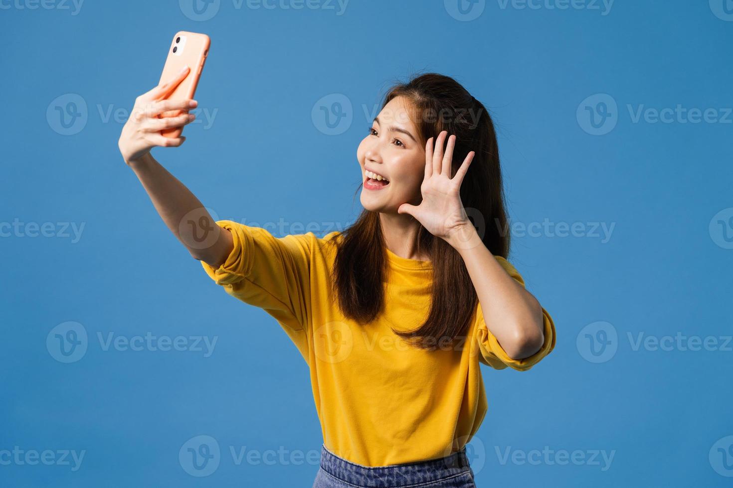 Aziatische vrouw selfie foto maken op slimme telefoon op blauwe achtergrond.