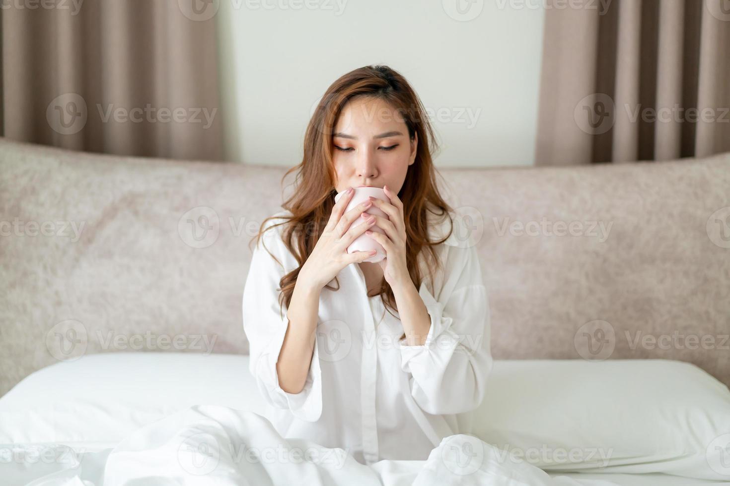 portret mooie vrouw wakker worden en koffiekopje of mok op bed houden foto