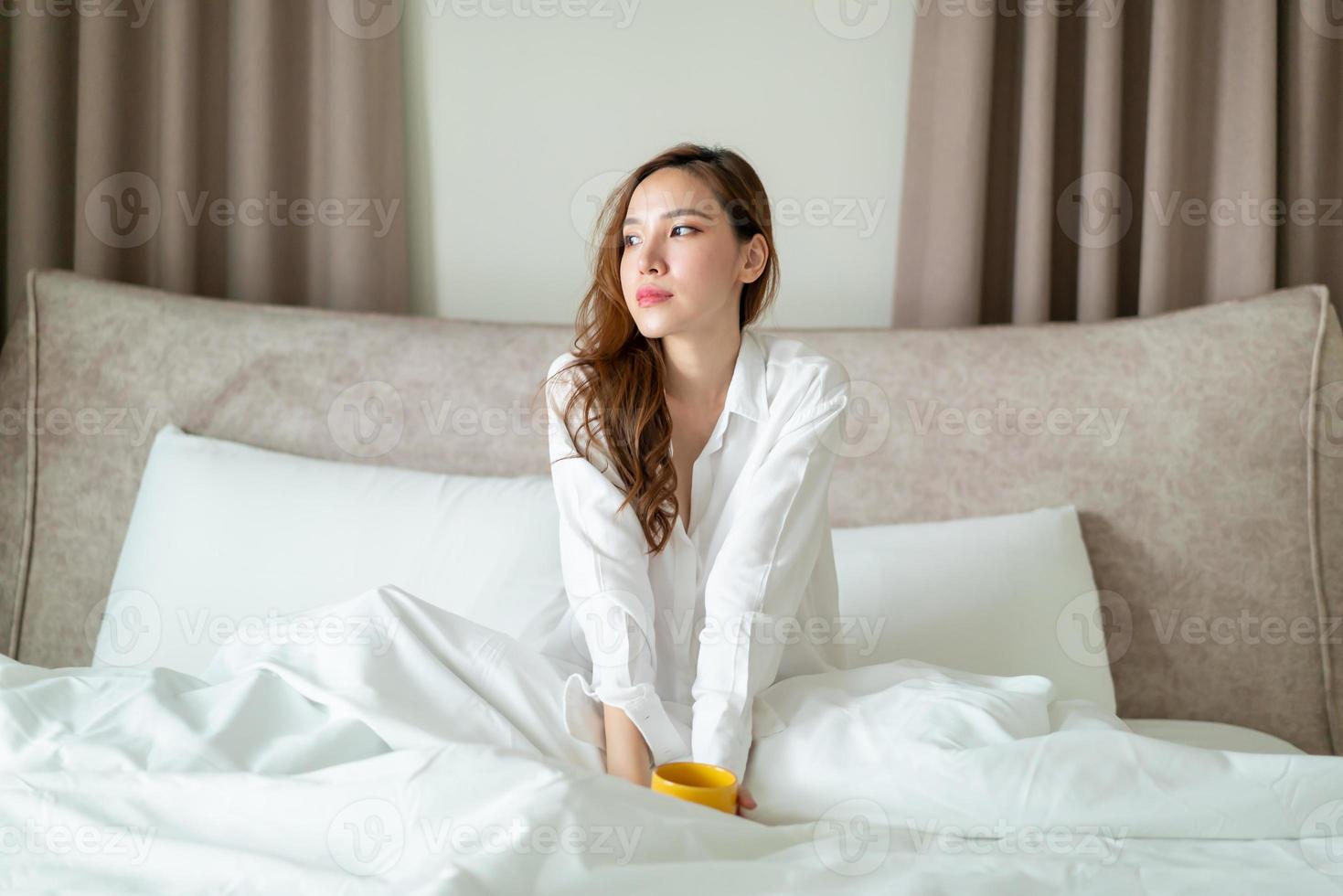 portret mooie vrouw wakker worden en koffiekopje of mok op bed houden foto