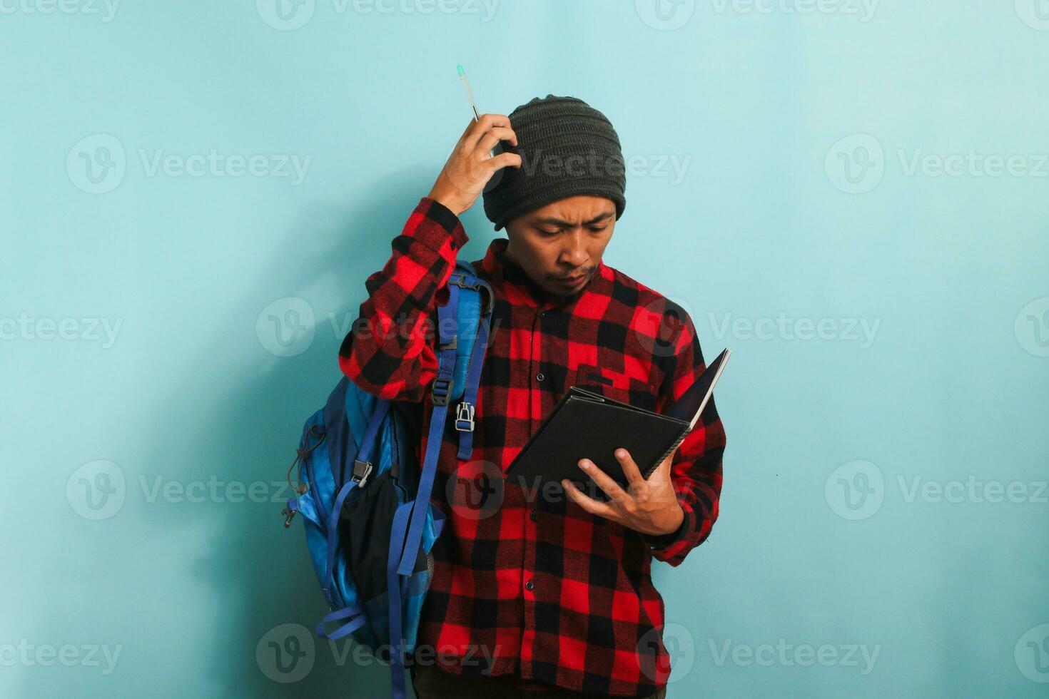 nadenkend jong Aziatisch leerling is diep in gedachte, op zoek ideeën terwijl staand tegen blauw achtergrond foto