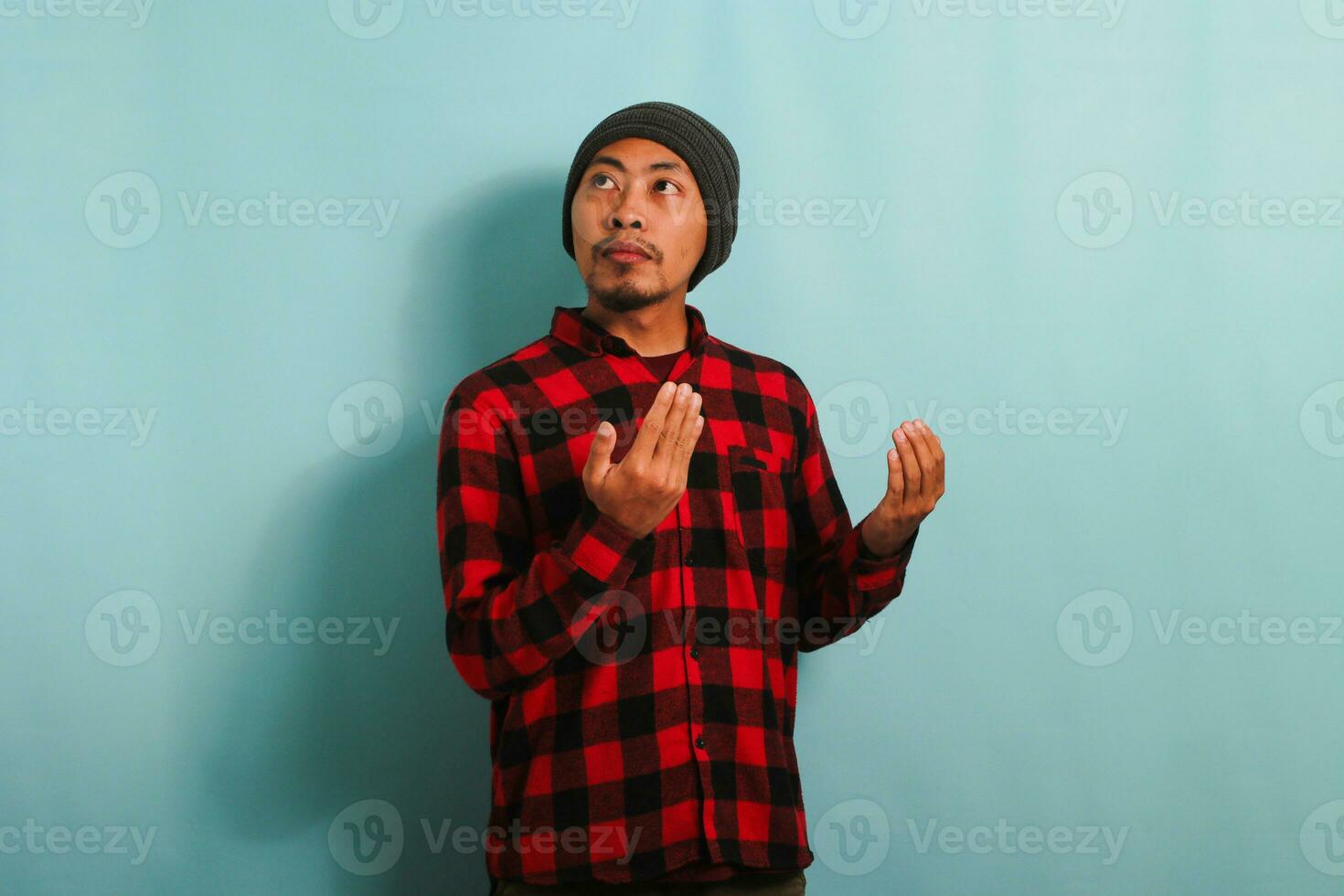 jong moslim Aziatisch Mens is bidden naar Allah, geïsoleerd Aan een blauw achtergrond foto