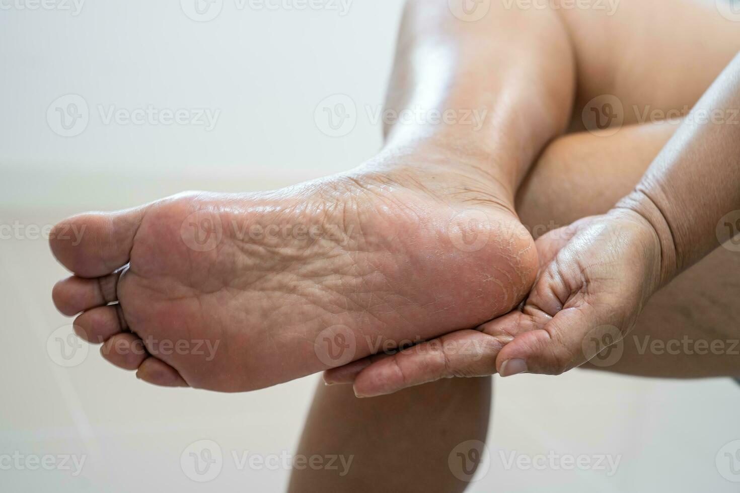Aziatisch vrouw zorg voeten met gebarsten en droog hiel- huid room Bij huis. foto