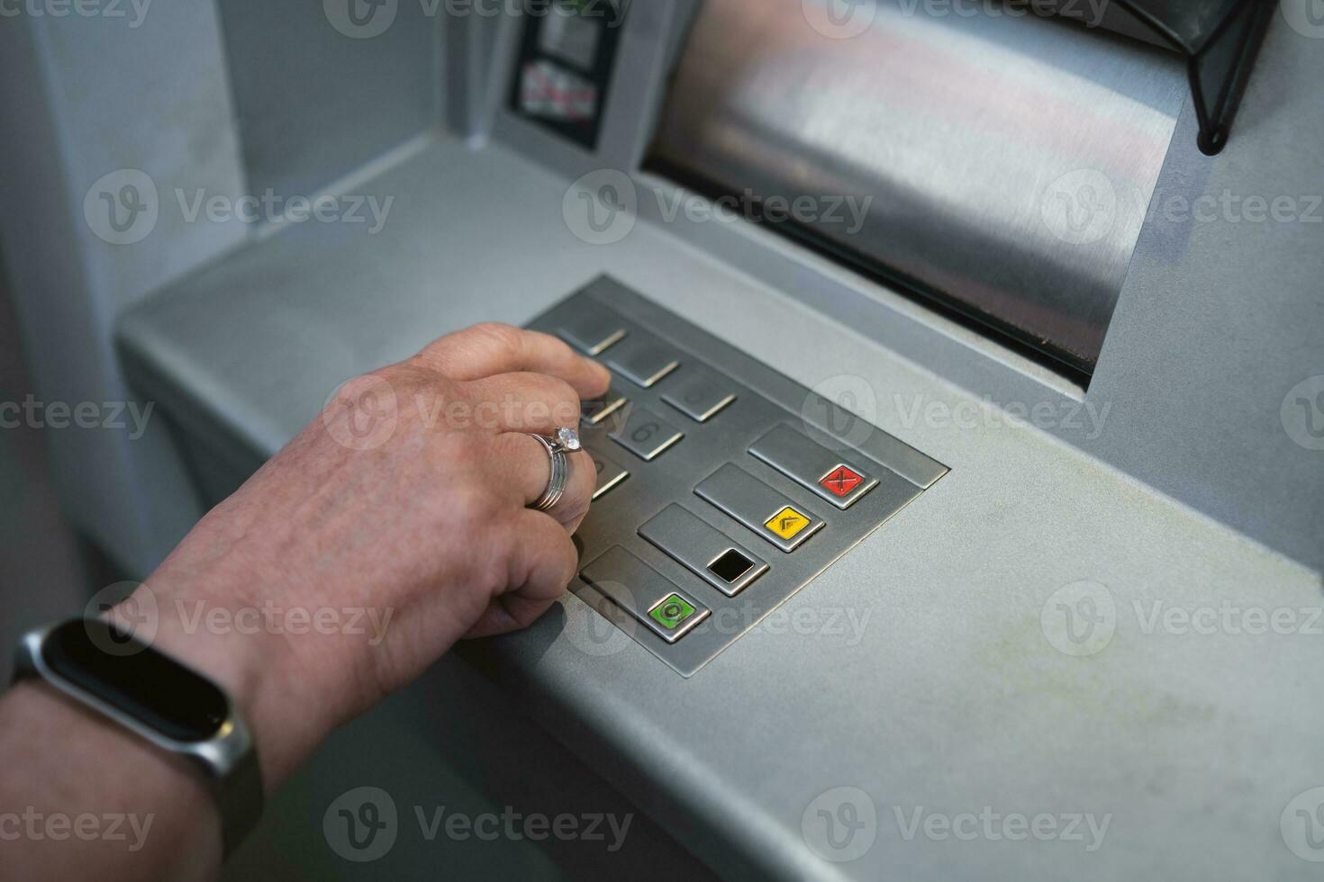 midden- oud vrouw gebruik makend van Geldautomaat drukken de pin veiligheid Aan de aantal kussen. foto