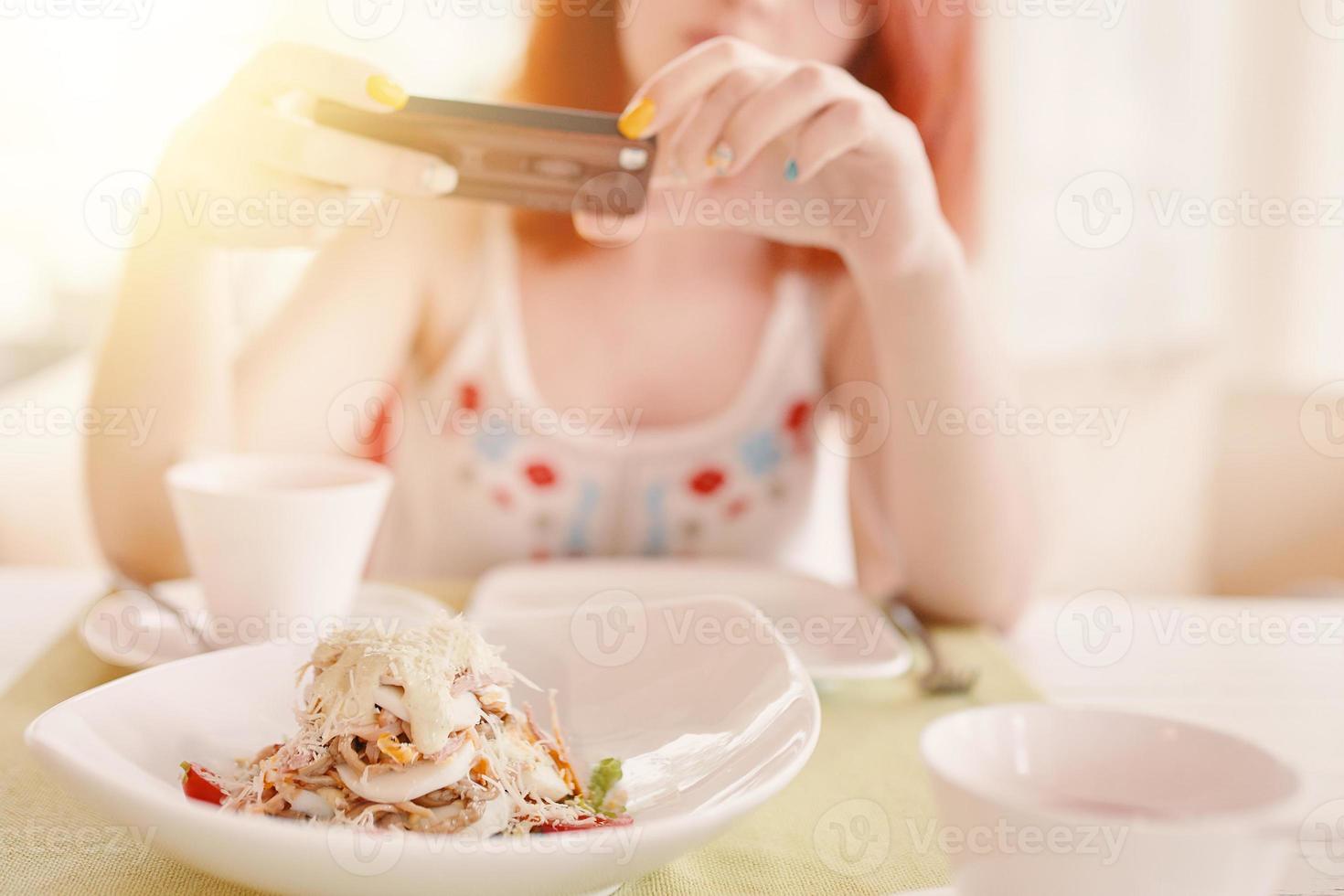 roodharige vrouw maakt foto's van salade op smartphonecamera foto