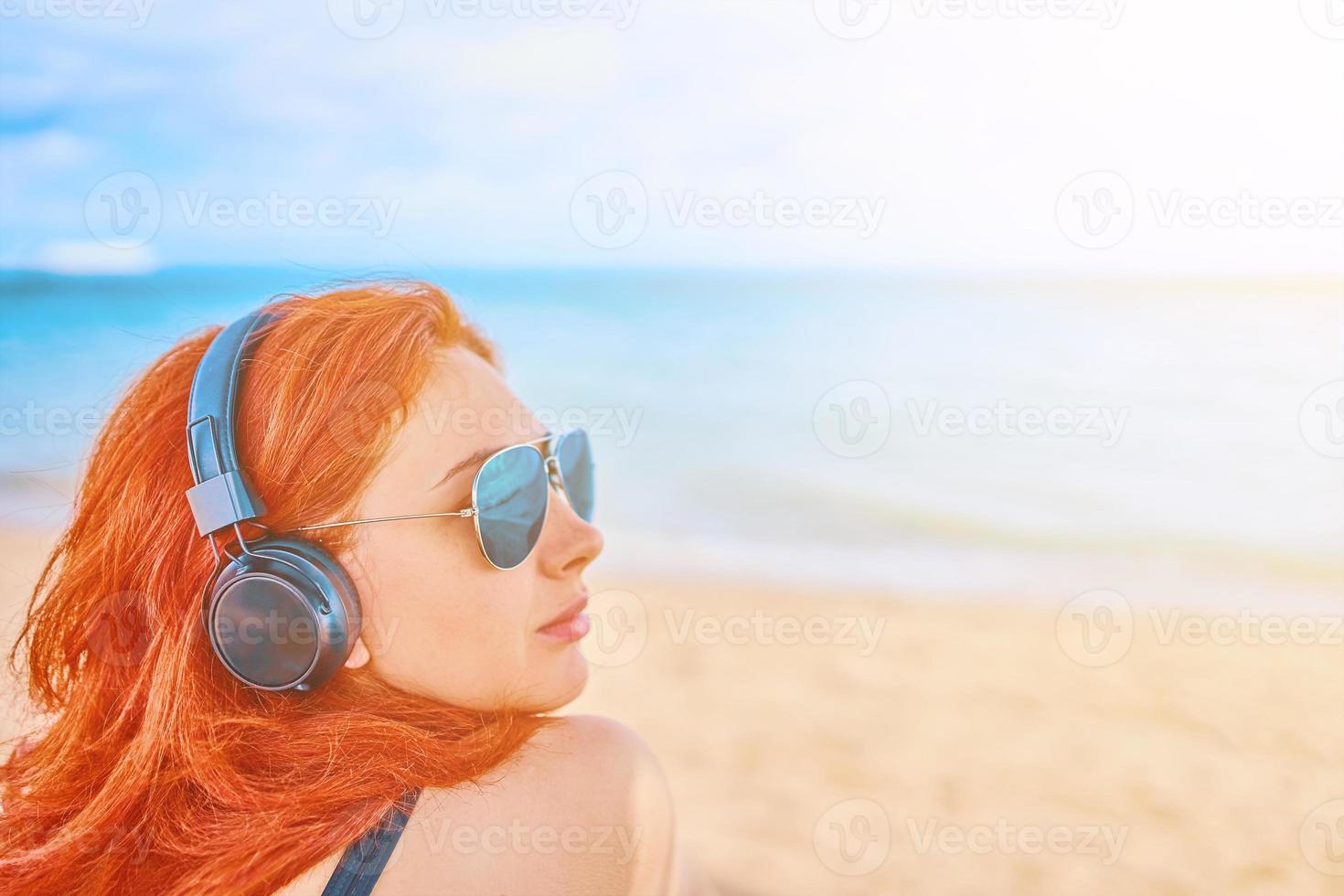 mooie vrouw in zonnebril luisteren naar muziek op het strand foto