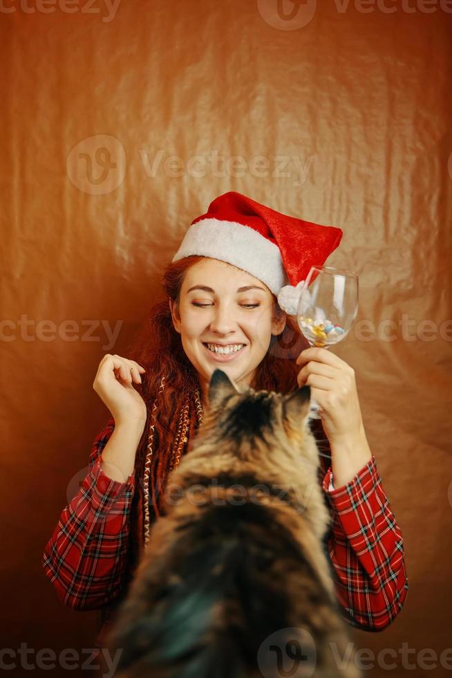 roodharige vrouw in kerstman hoed en pluizige kat foto