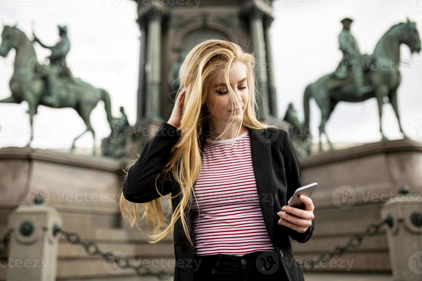 jonge vrouw met mobiele telefoon op straat in wenen, oostenrijk foto