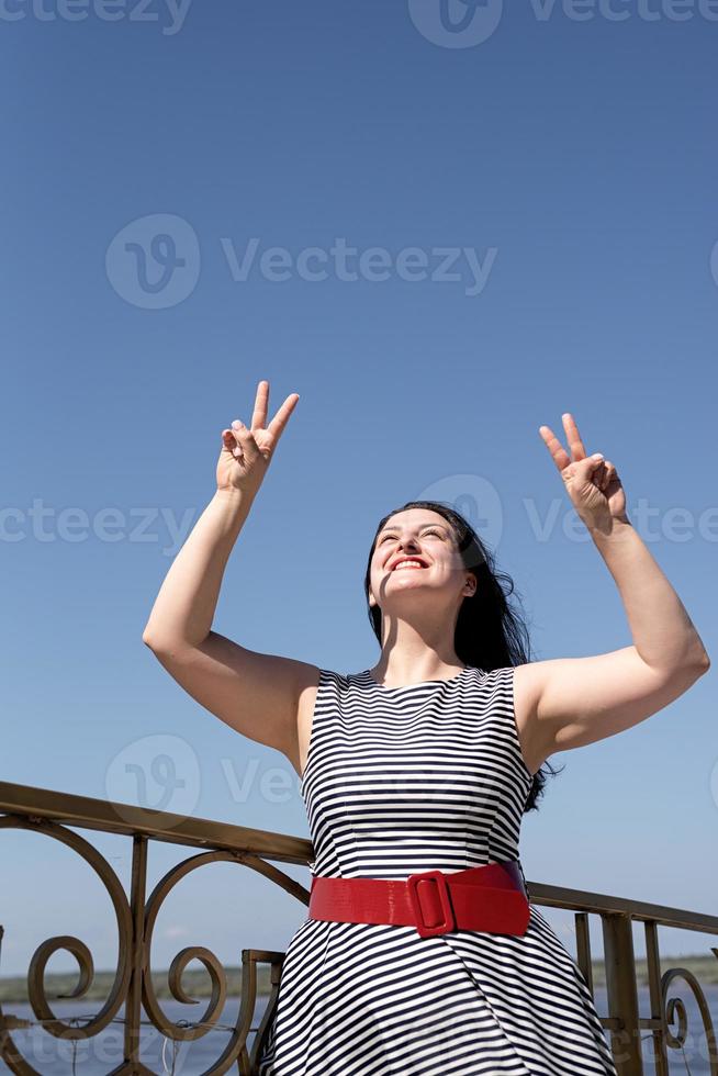 mooie jonge vrouw opende haar handen naar de blauwe lucht foto