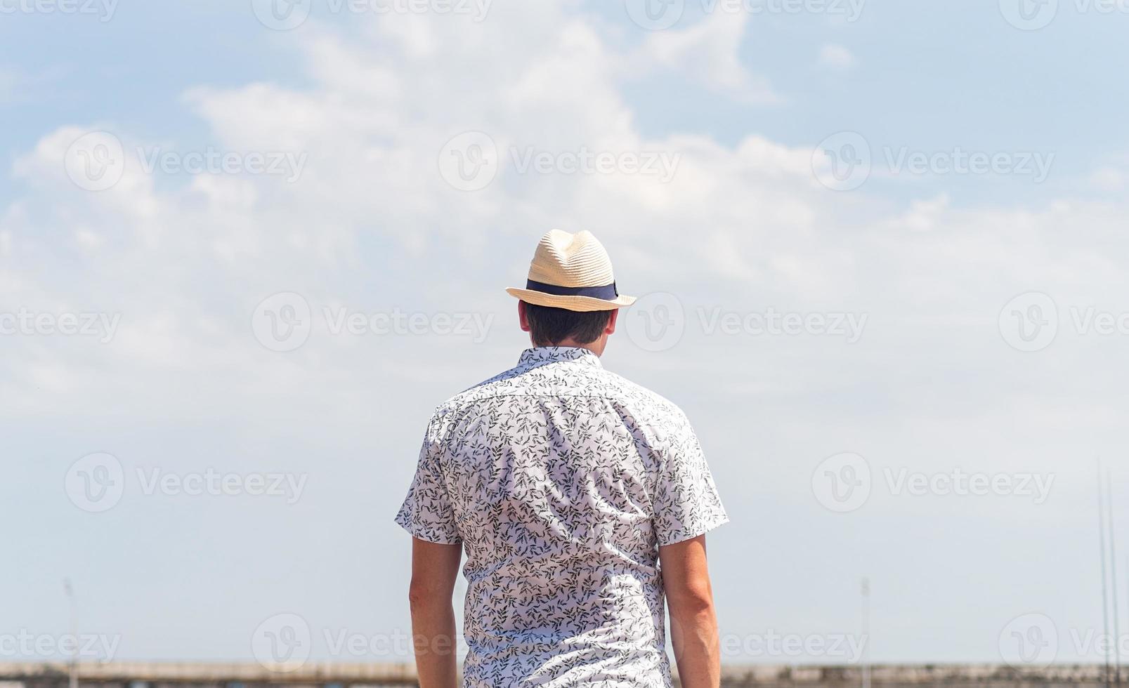 achteraanzicht van een man in shirt en zomerhoed die naar de lucht kijkt foto