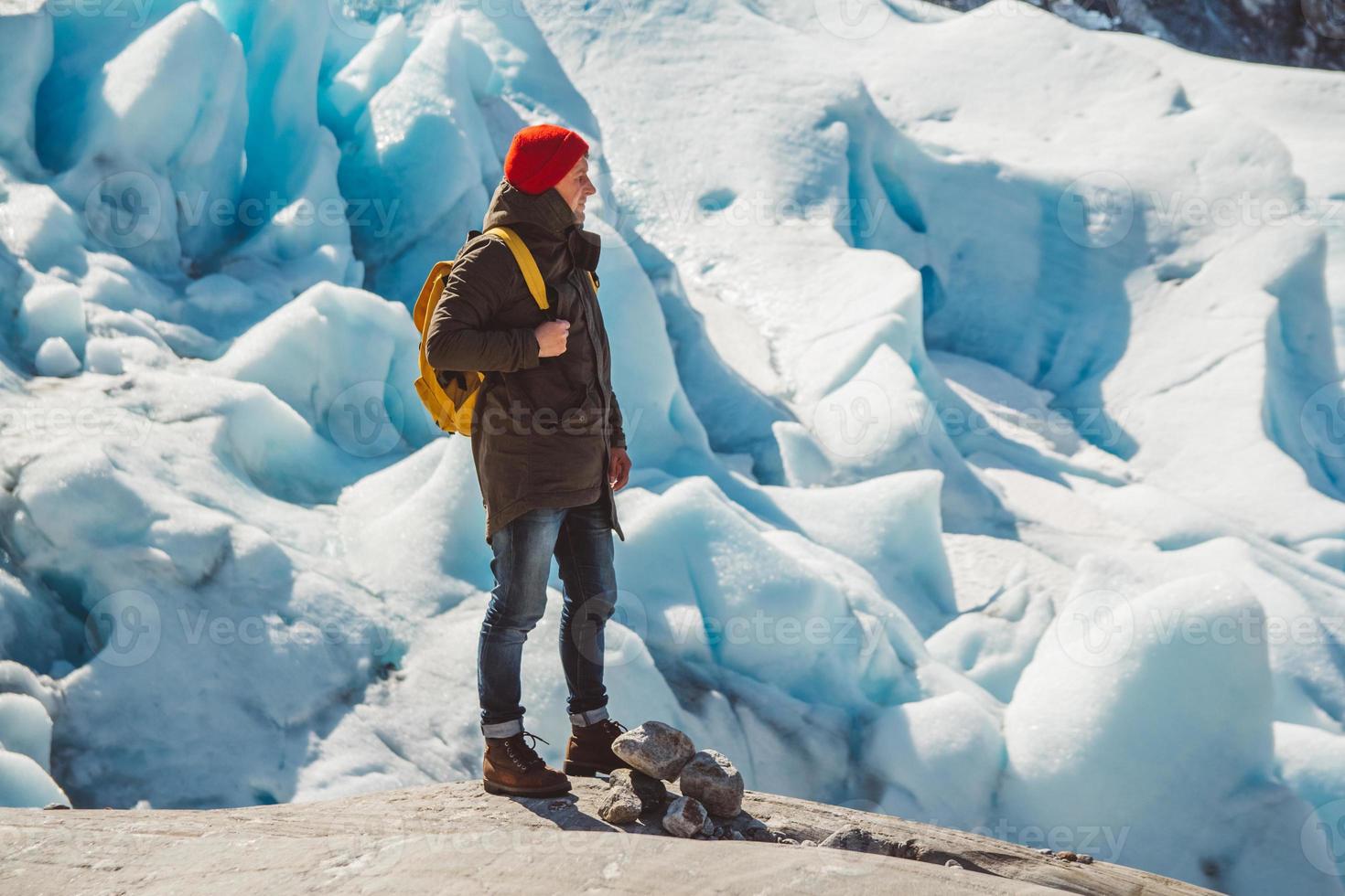 reiziger man staande op een rots op de achtergrond van een gletsjer foto