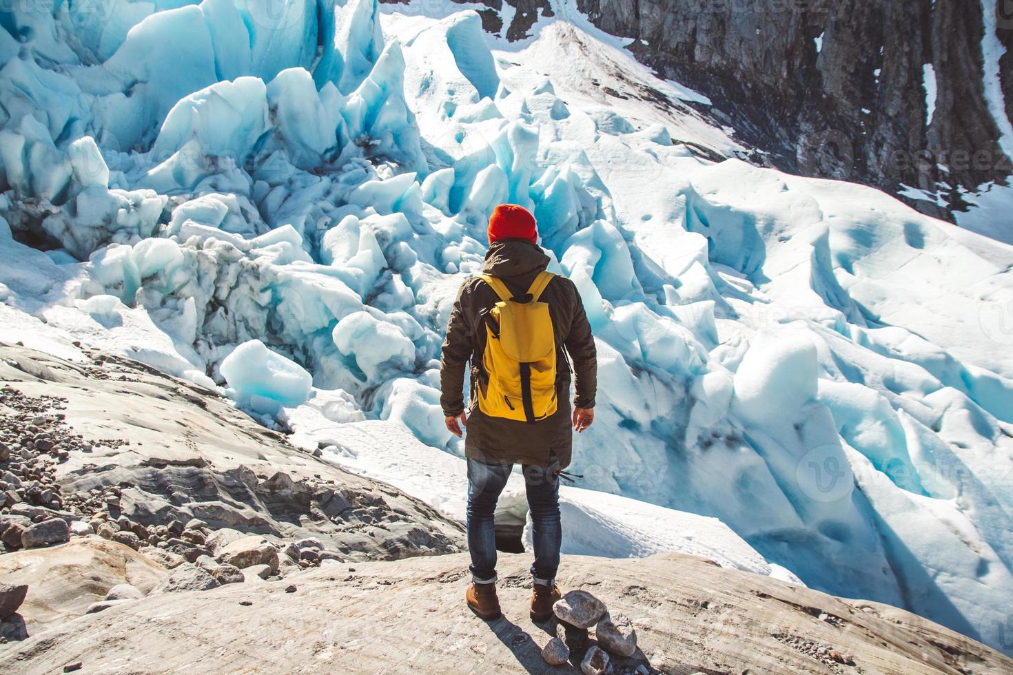 reiziger man staande op een rots op de achtergrond van een gletsjer foto