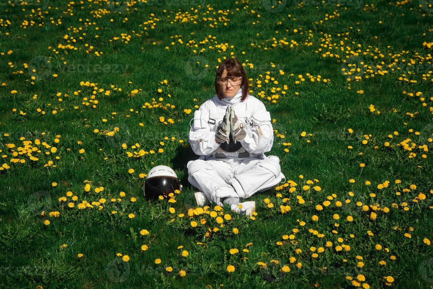 vrouwelijke astronaut zonder helm zit op een groen gazon tussen bloemen foto