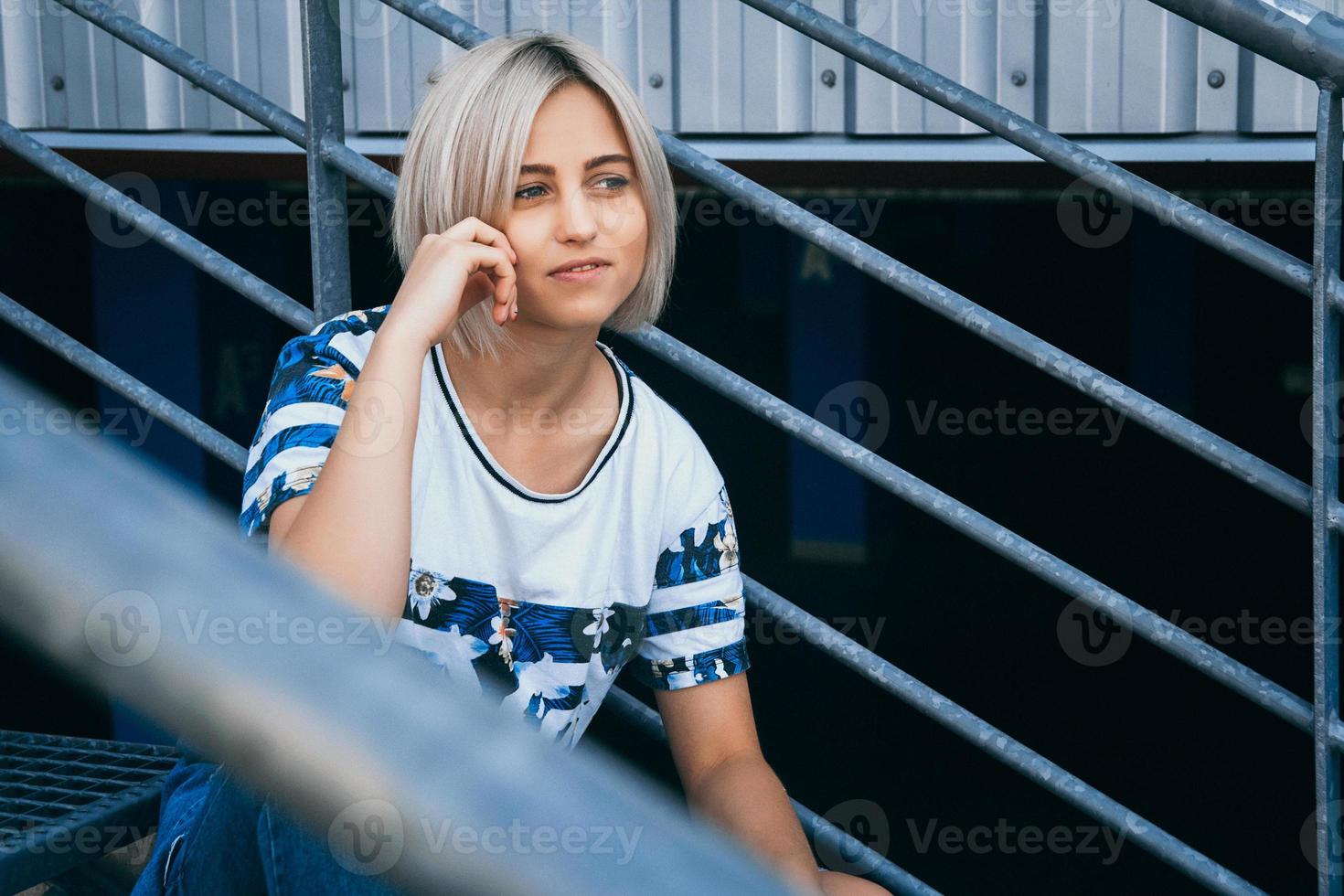 vrouw met kort wit haar in stedelijke stijl zit op de metalen trap foto